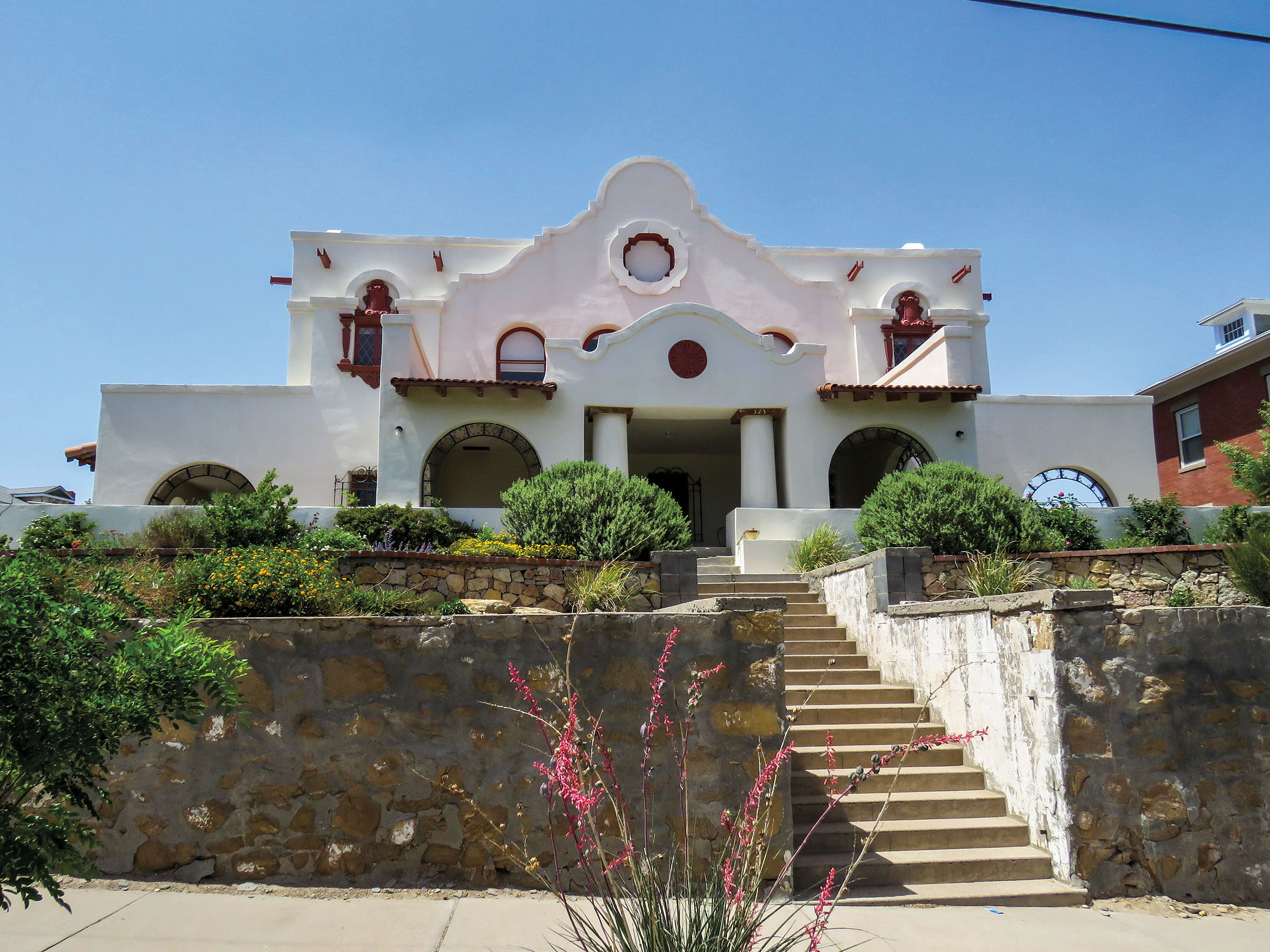 The exterior of a white Spanish-style building with a large entrance and staircase