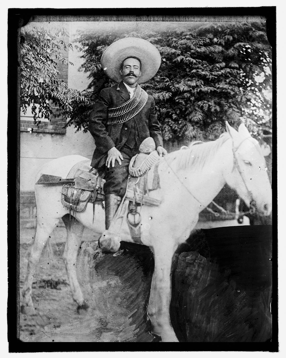 A black and white photograph of a man on a white horse