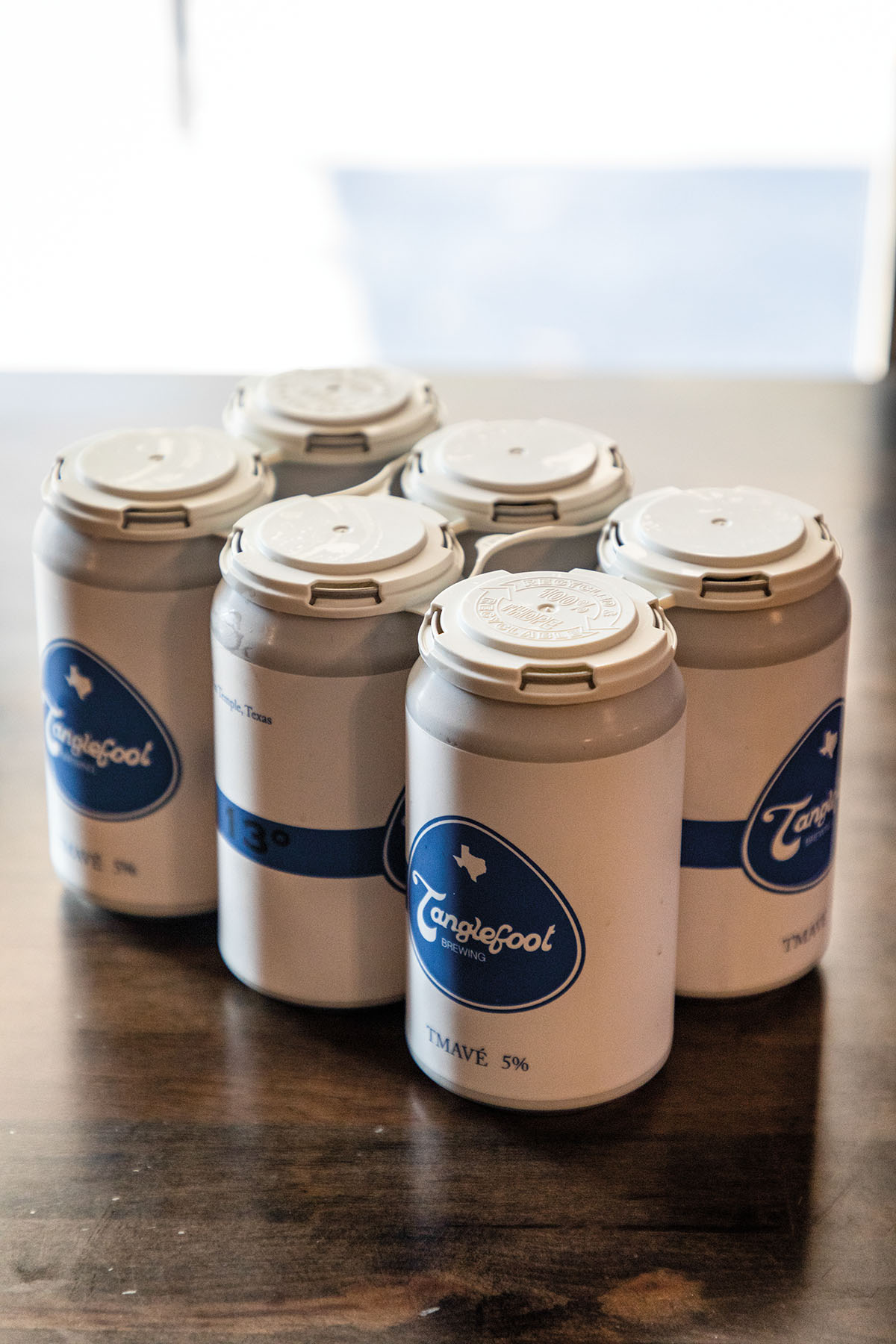 A small pack of beer cans on a wooden table