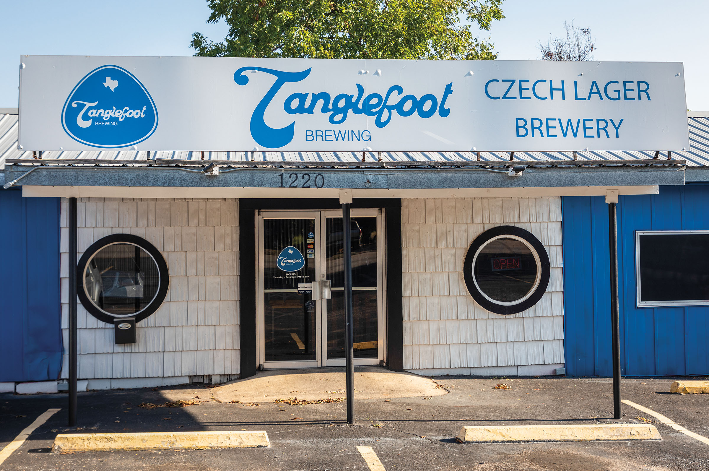 The exterior of a bright blue and white building with a sign reading 'Tanglefoot Brewing: Czech Lager Brewery'