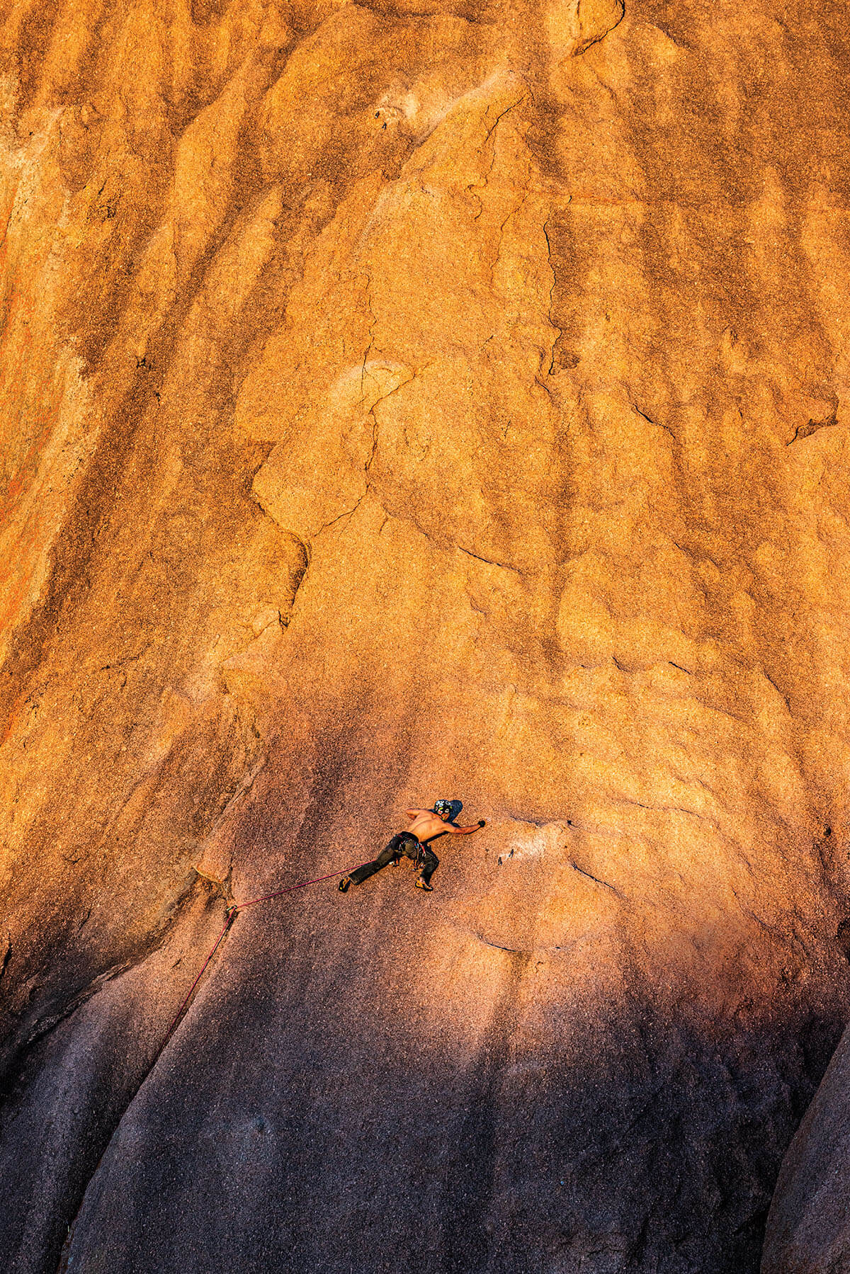 A person scales the side of a large rock face.