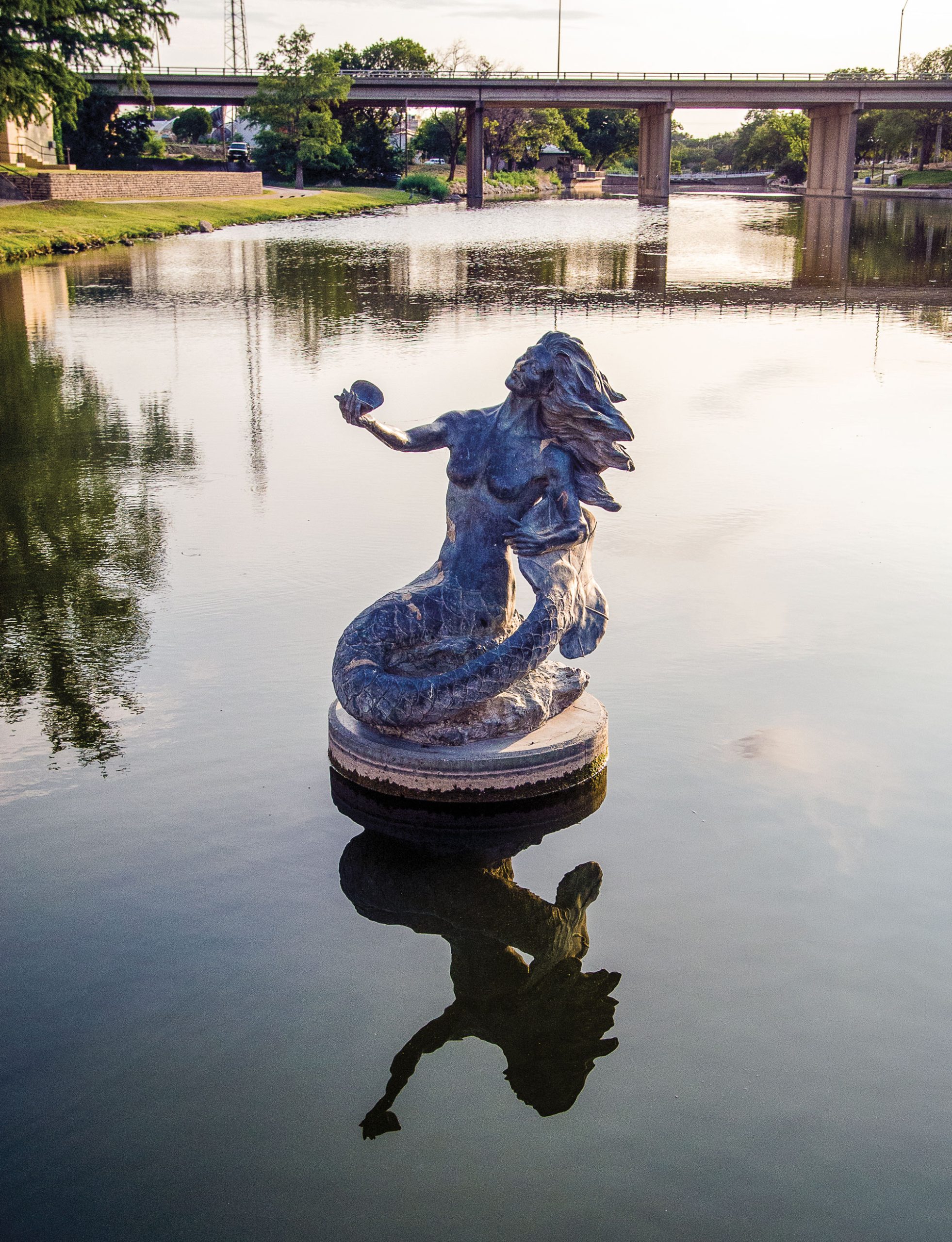 A statue of a mermaid in the middle of a body of water
