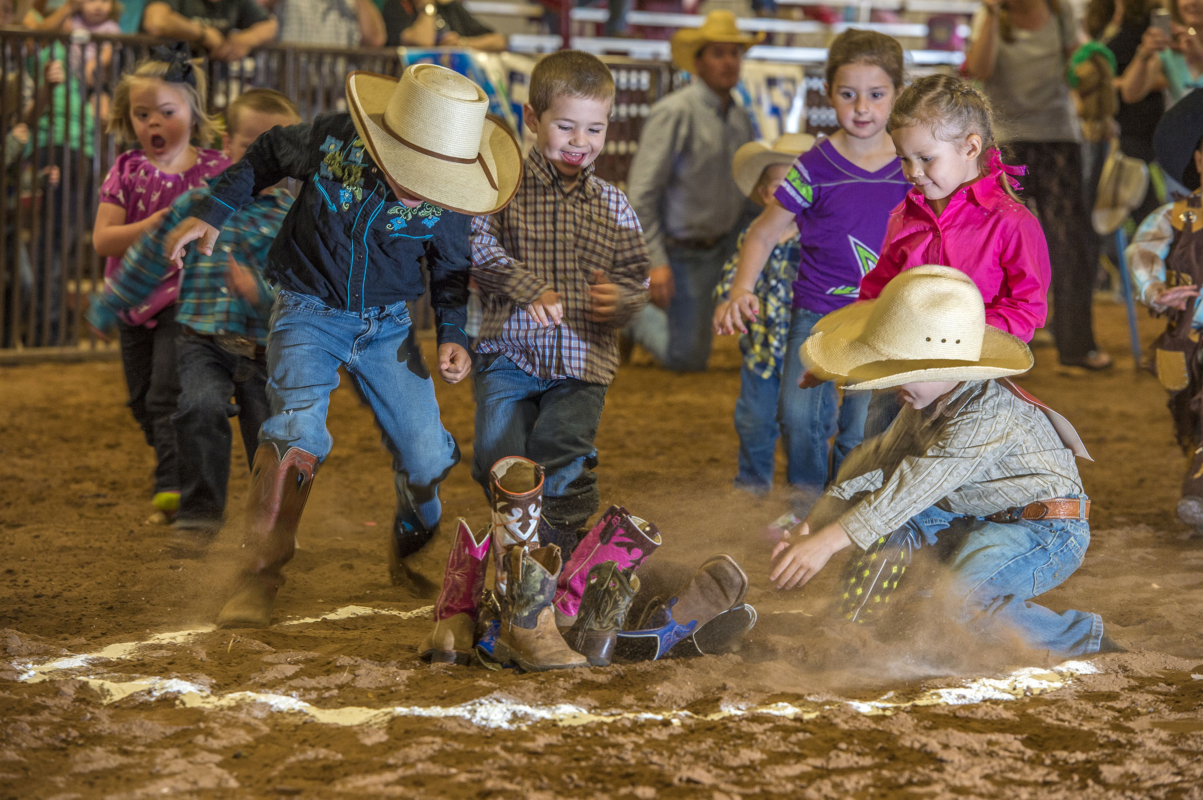 A group of children grab for boots in a dirt arena