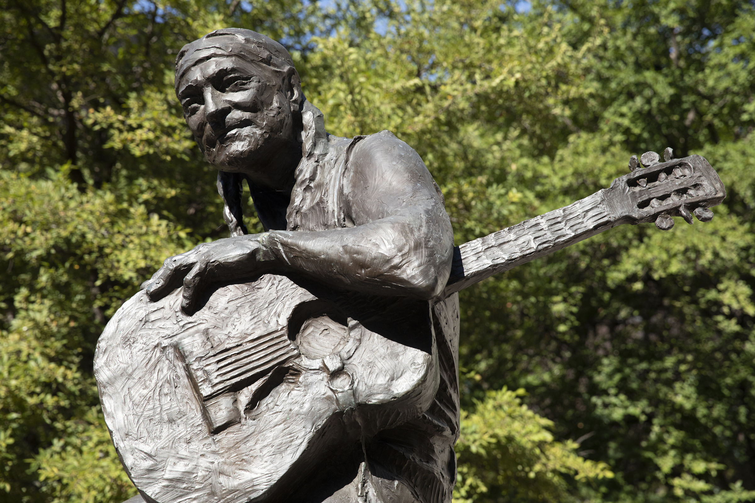 A statue of Willie Nelson sitting with a guitar