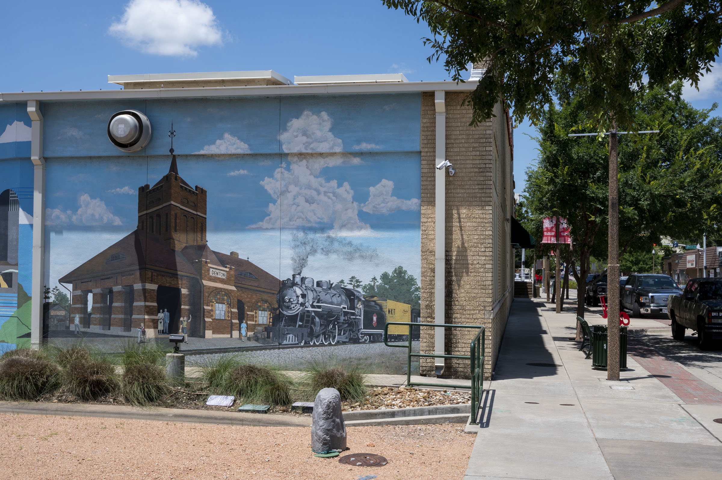 A mural featuring a small town scene on the side of a single-story building