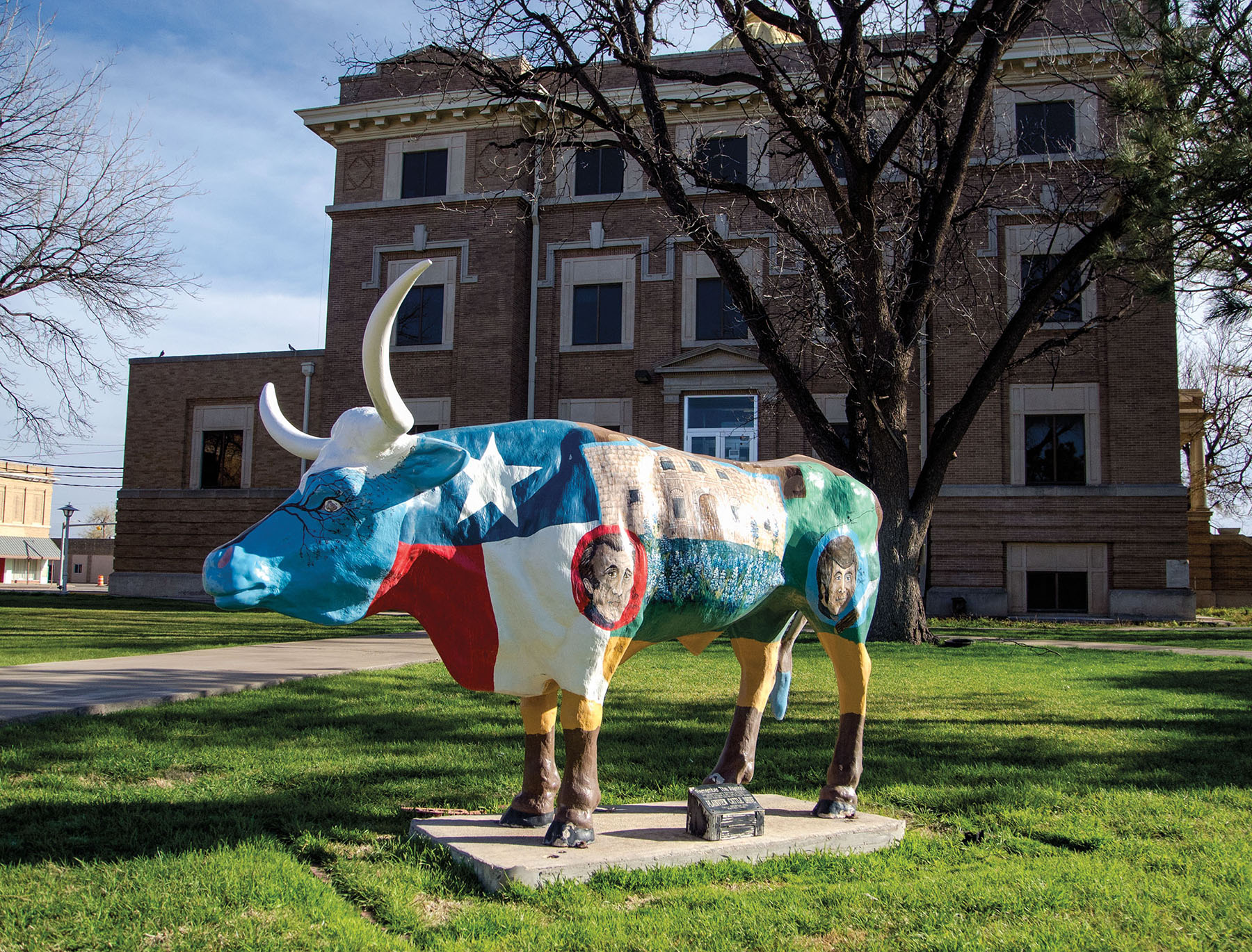 A brightly-painted cow with multiple symbols, including the flag of the state of Texas