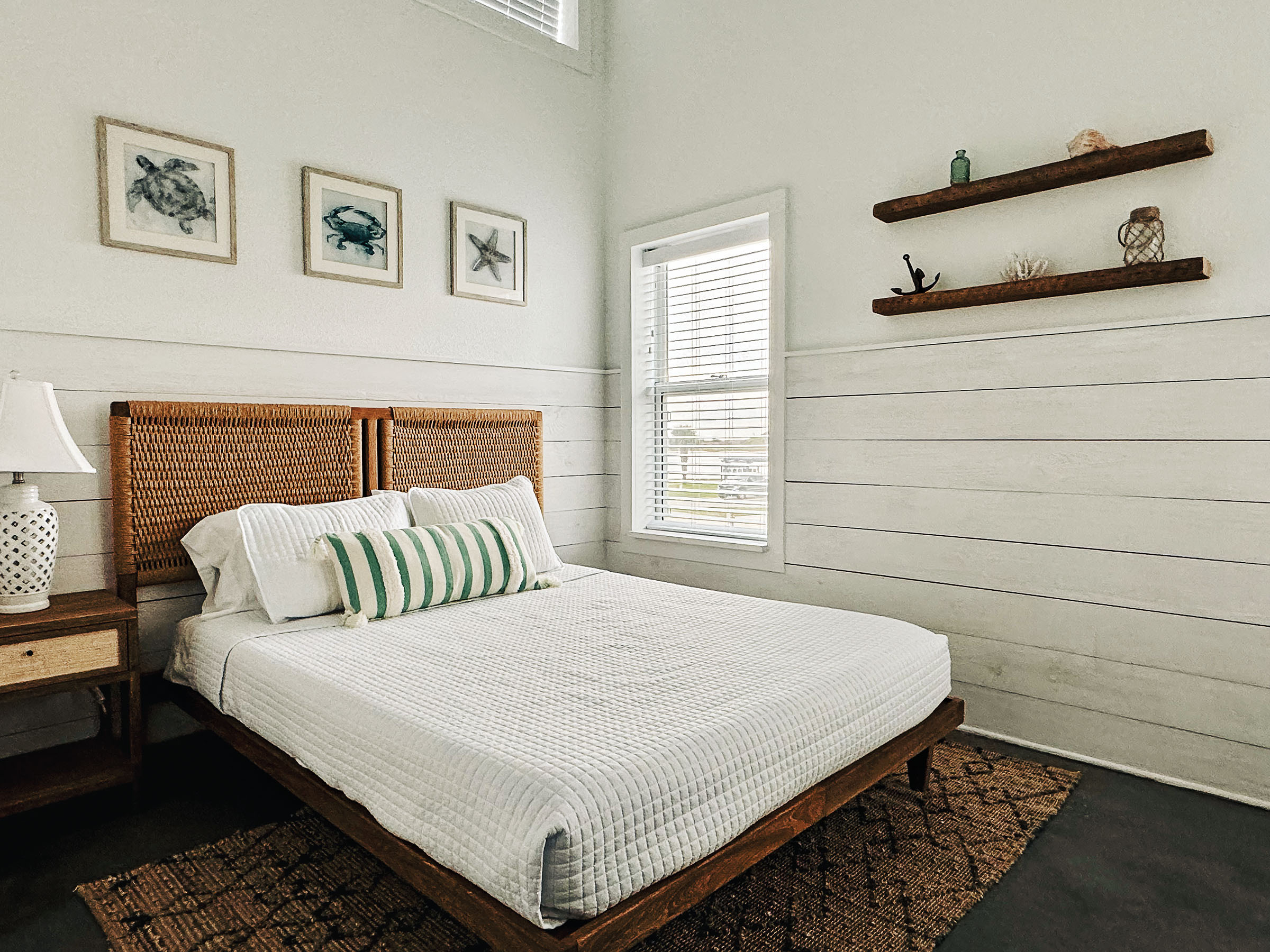 A white comforter on a wooden bedframe underneath wood paneling