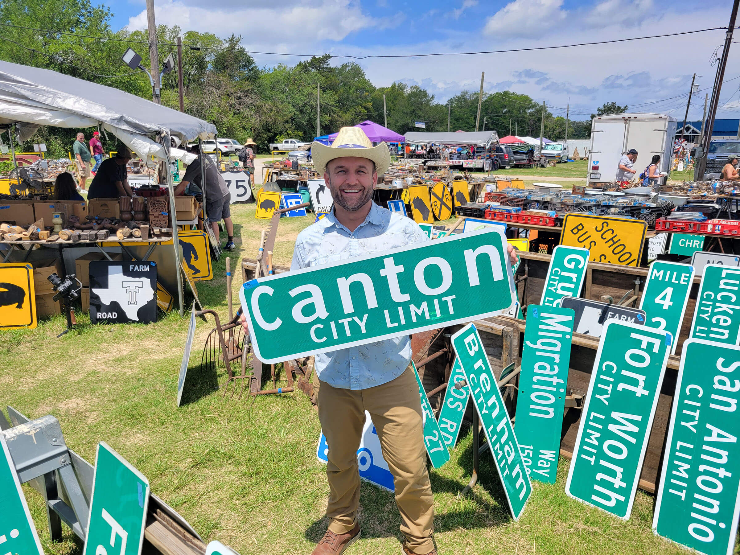 A man holds a large green sign reading "Canton City Limit"