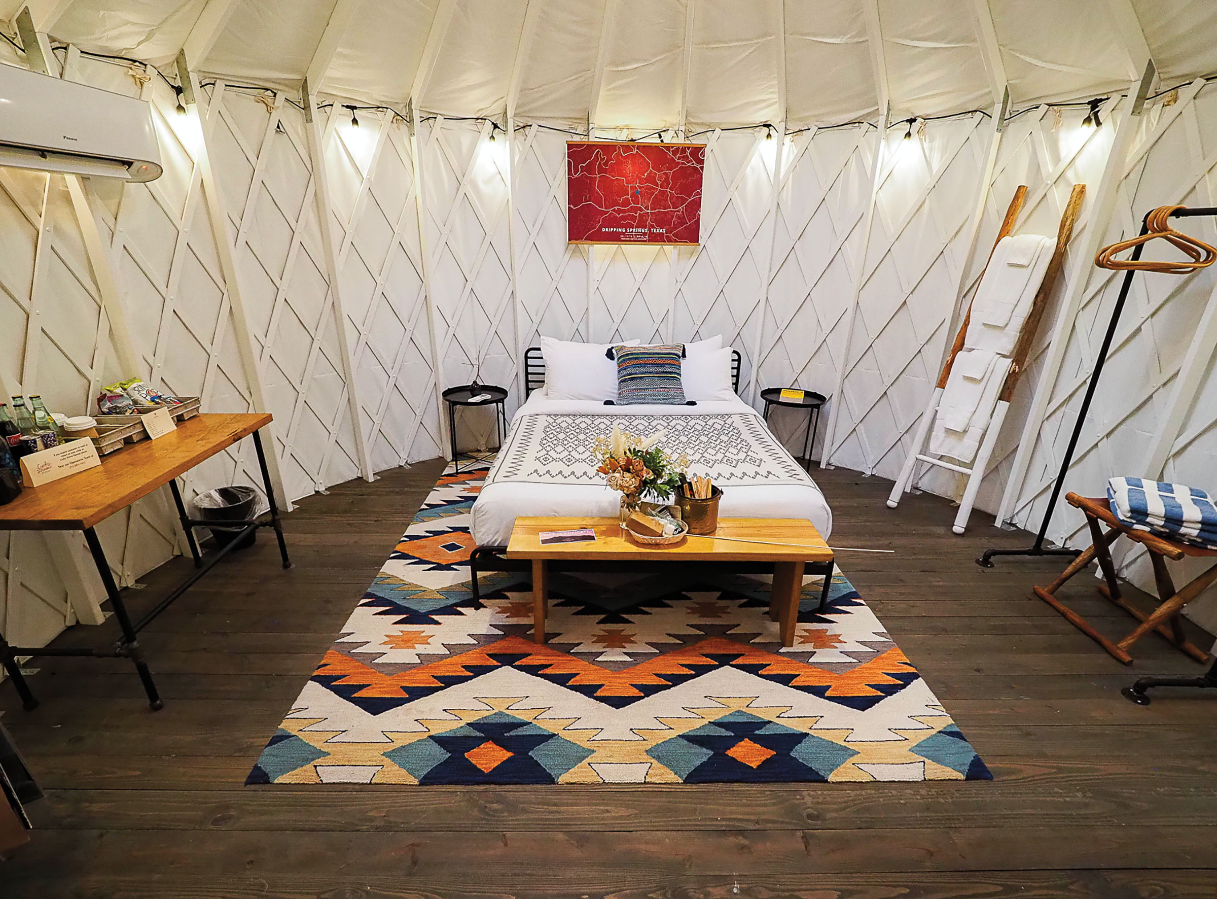 The inside of a glamping tent, with a large bed on a colorfully-patterned rug