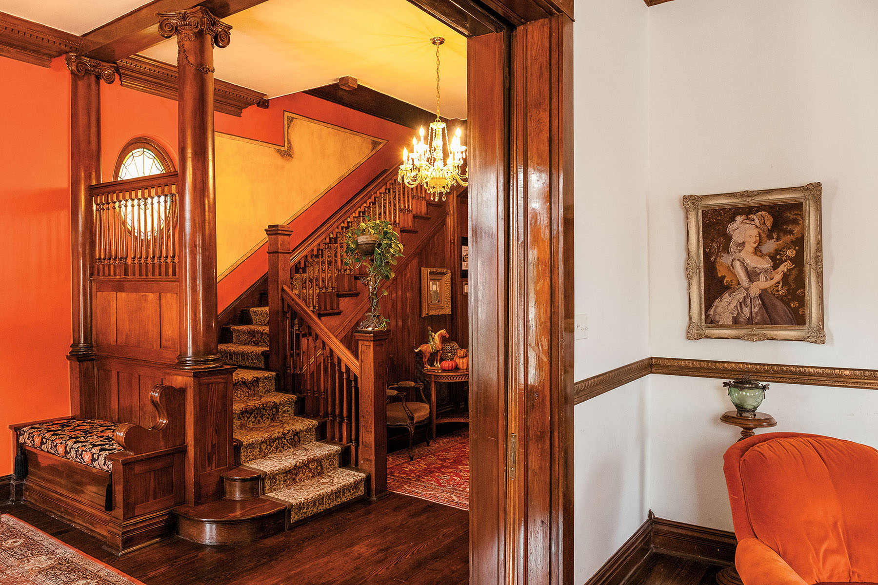 The interior of a mansion with rich wood paneling, warm lights, and framed pictures