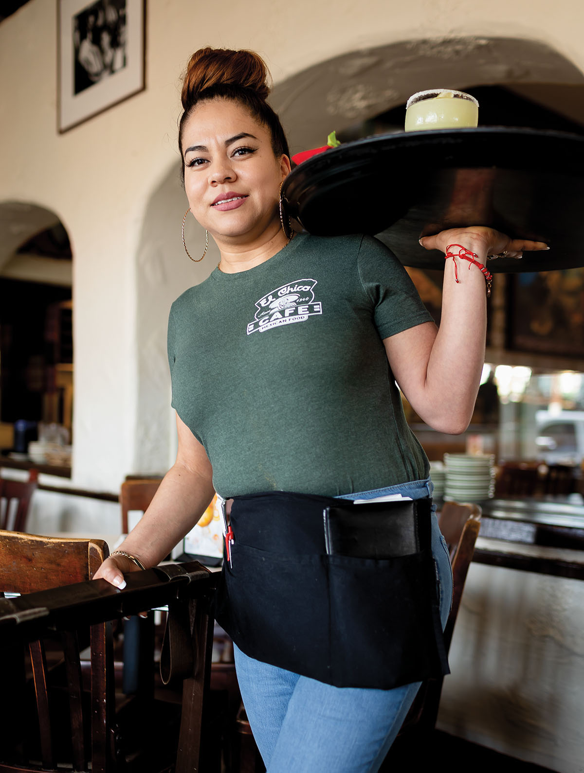 A waitress holds a large platter of food inside of a restaurant