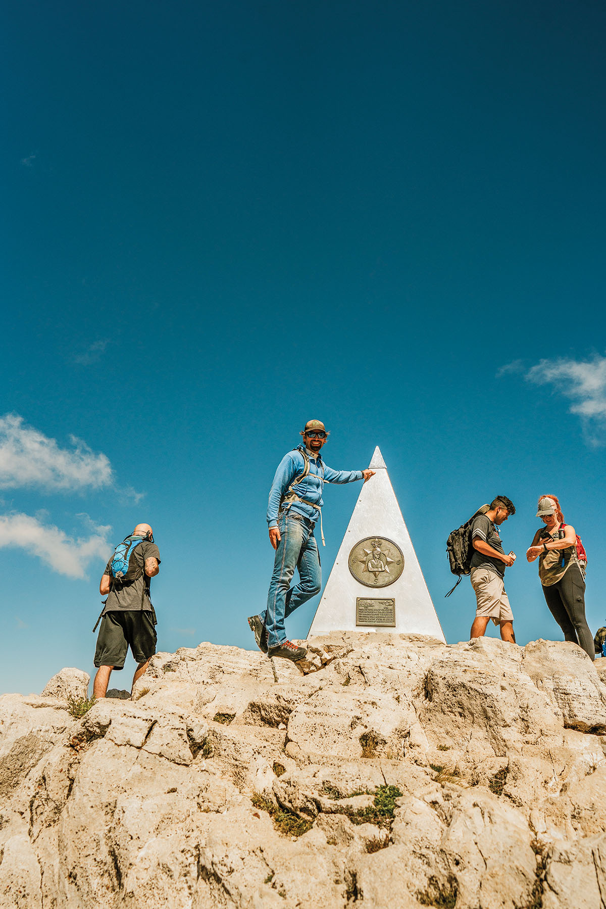 A group of hikers stand at the summit obelisk of Guadalupe Peak