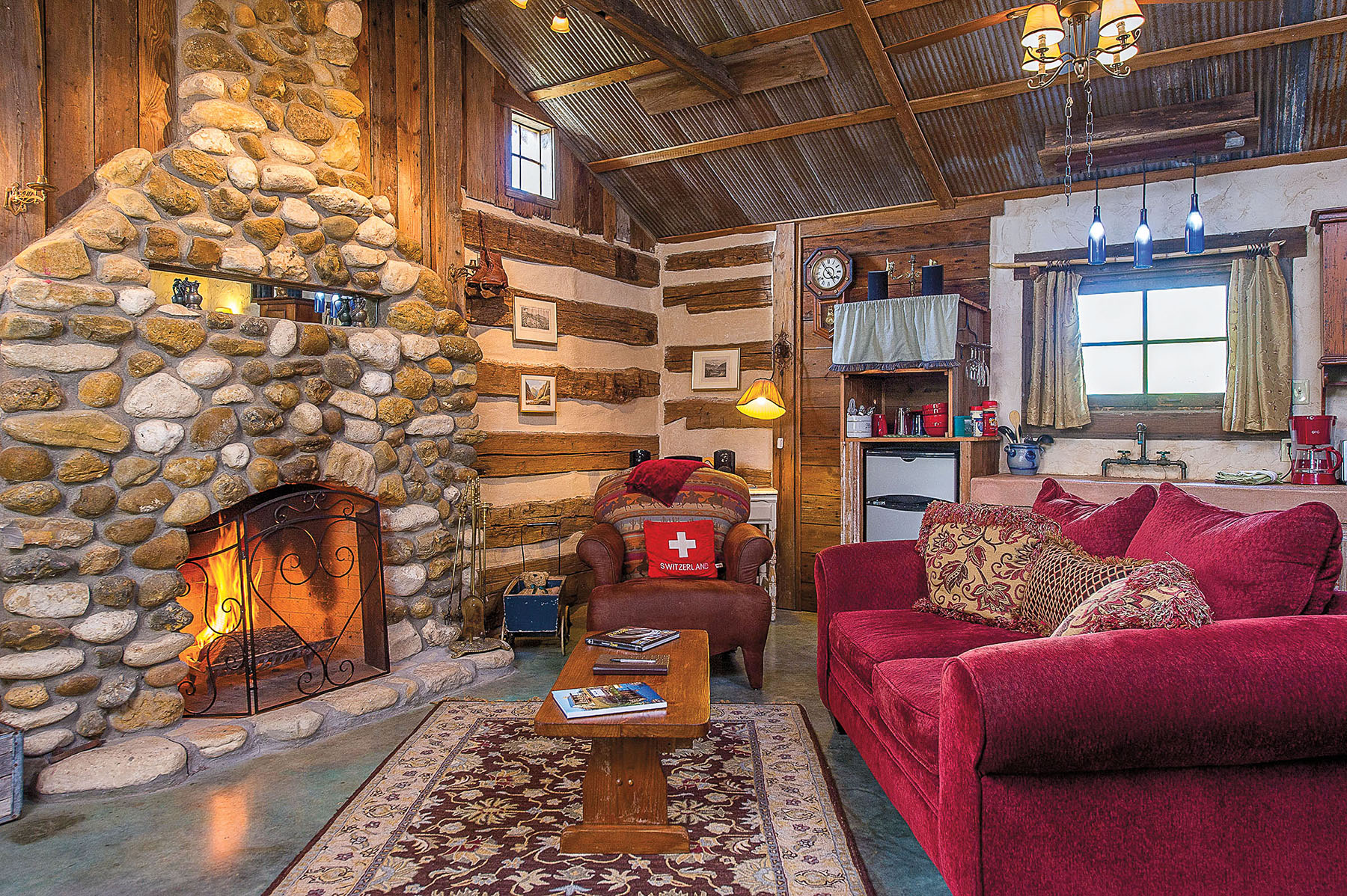The interior of a lodge with a large stone fireplace and red furniture