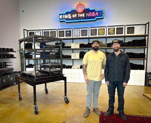 Brothers Matt and Caleb Johnson stand inside a showroom with their ironworks and brand T-shirts in the background
