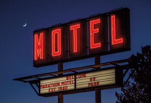 A tall neon red hotel sign reading "Motel" in front of a starry sky