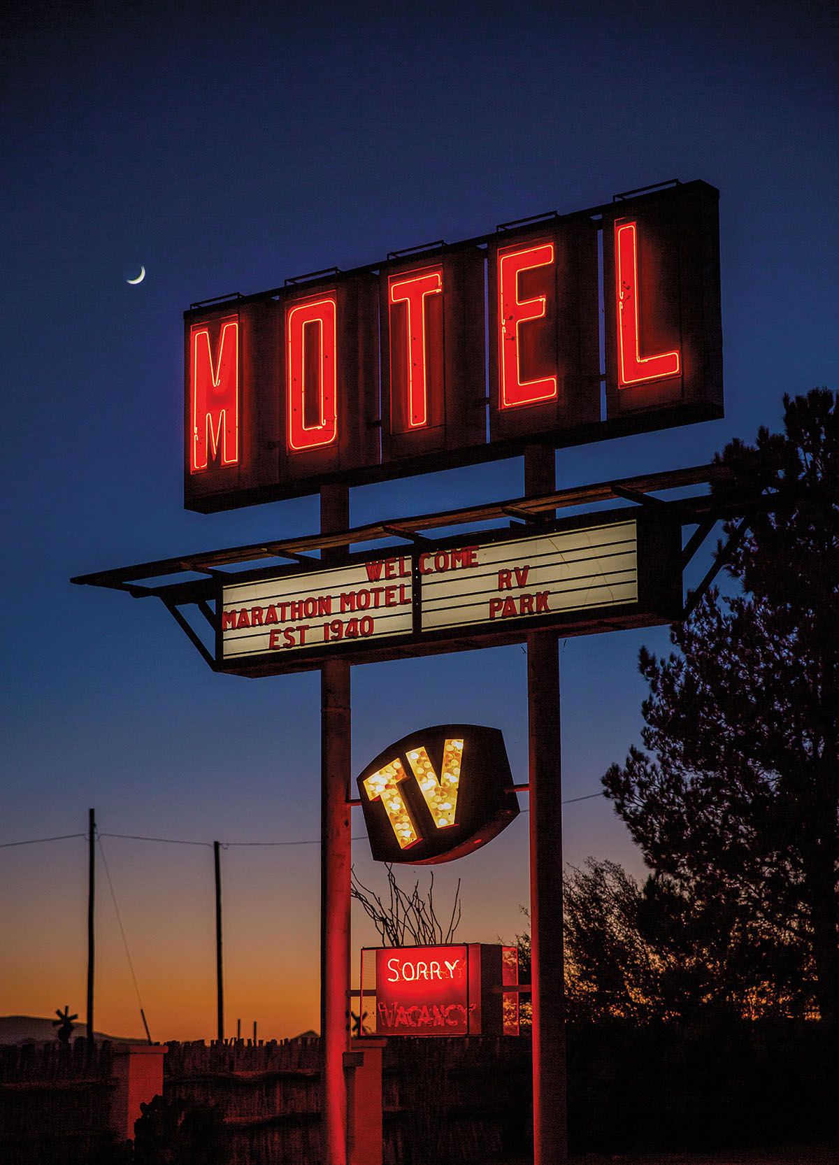 A tall neon red hotel sign reading "Motel" in front of a starry sky