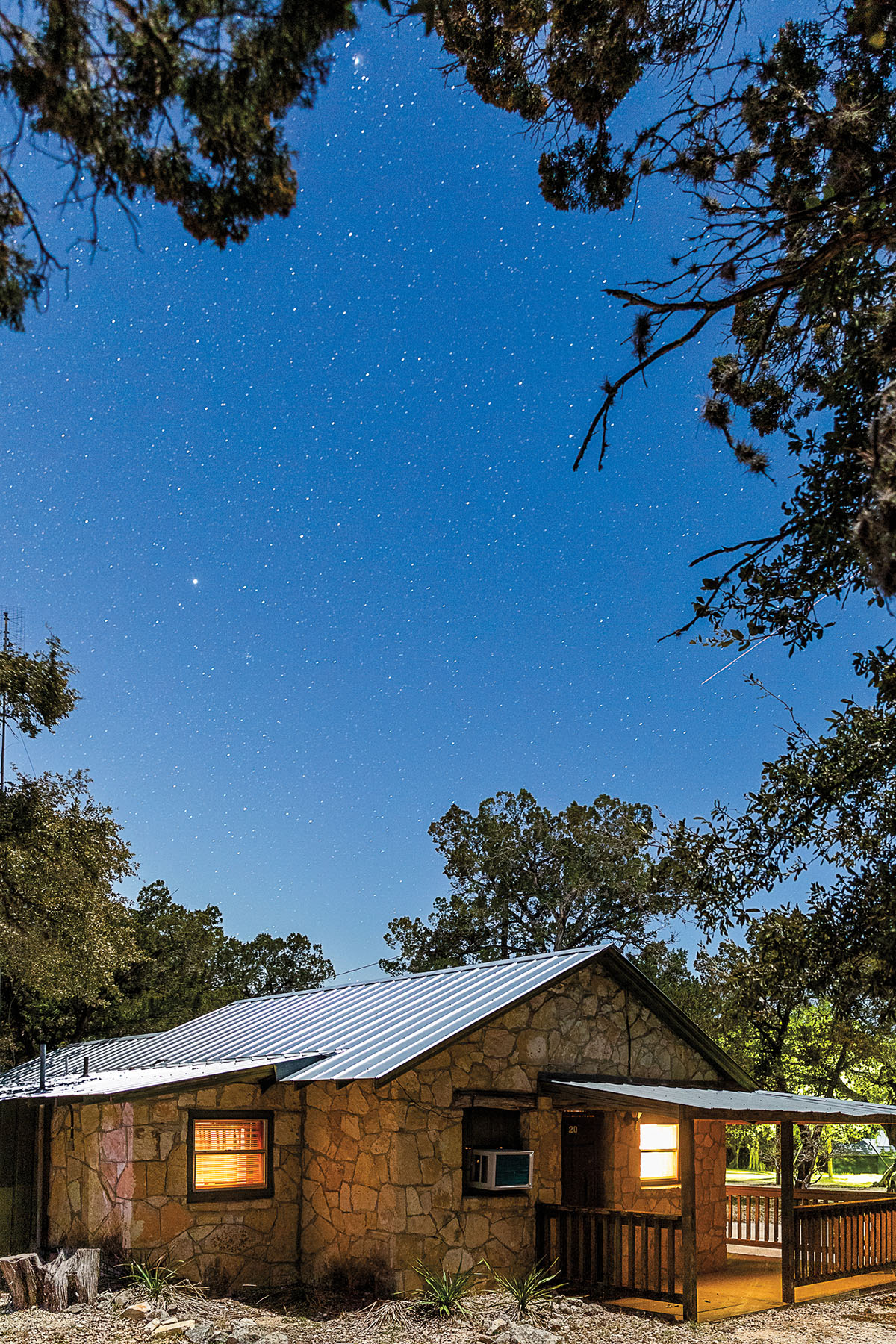 The exterior of a small cabin under a deep blue and starry sky