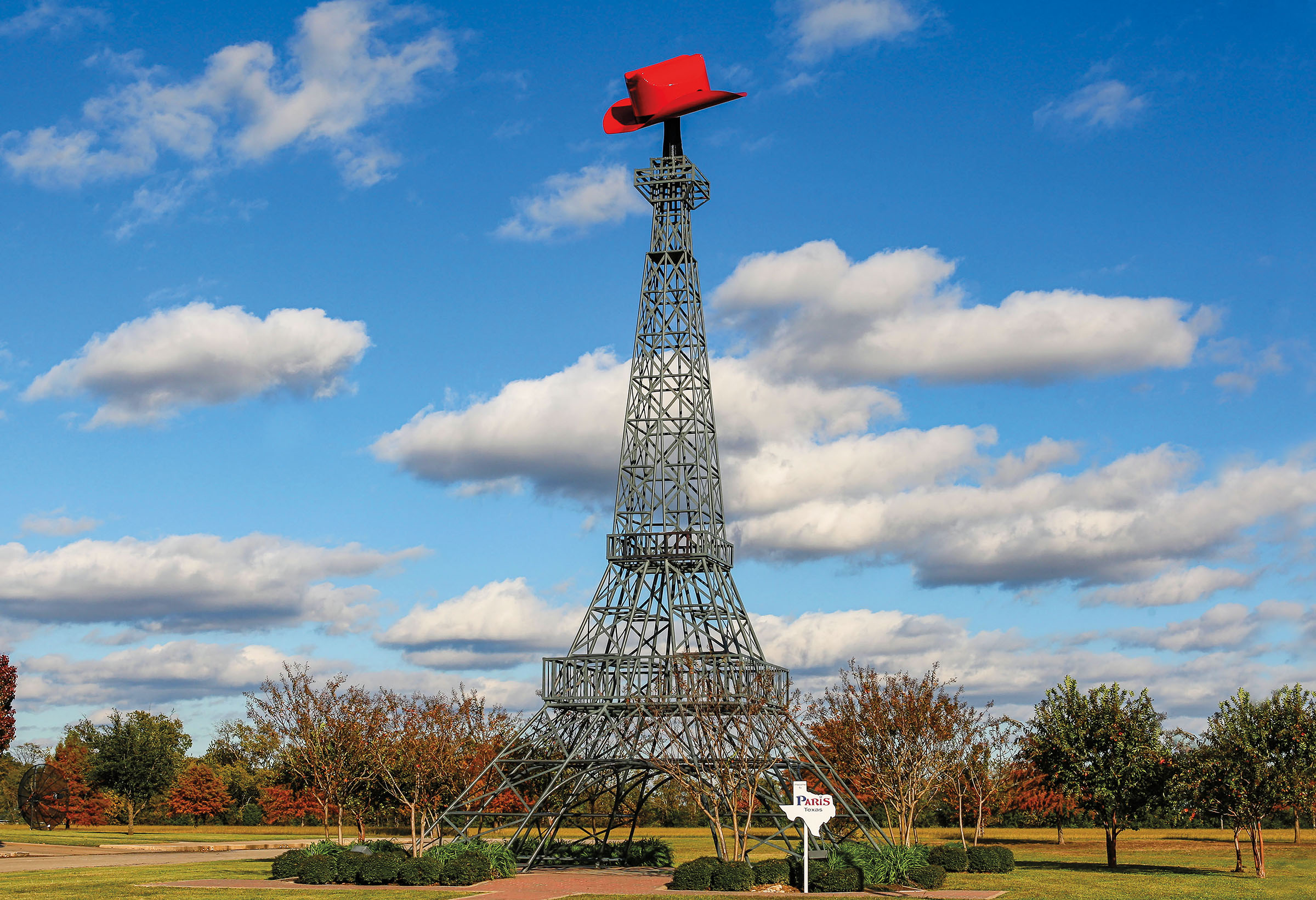 A replica Eiffel tower with a small red cowboy hat