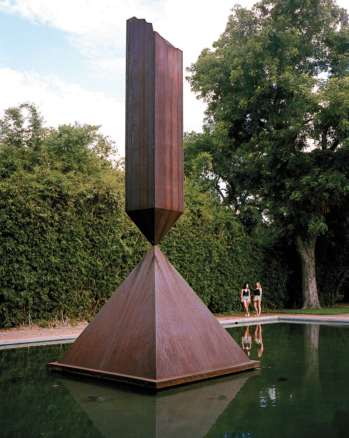 A large, dark, obelisk shaped sulpture in a fountain