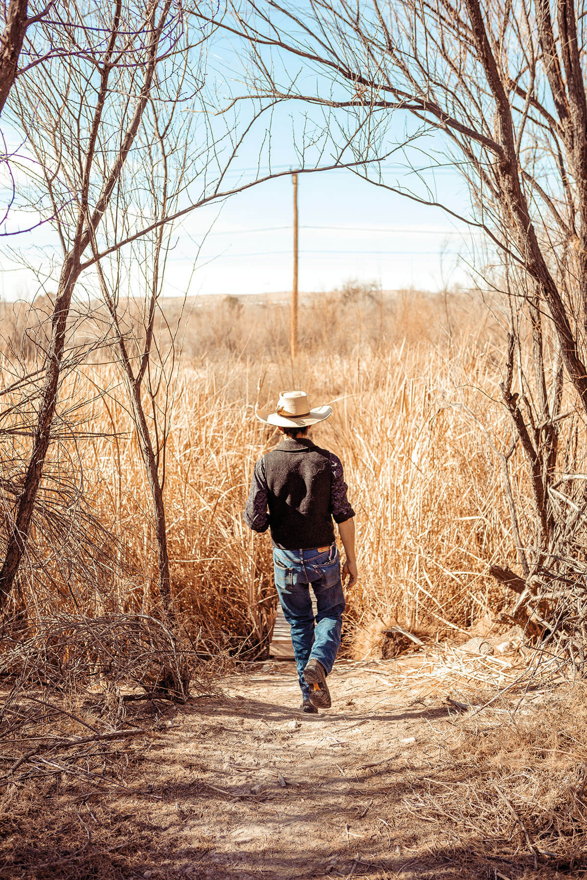 A man in a cowboy hat walks away from the camera