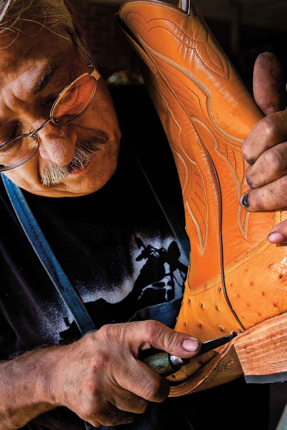 A man carefully works the leather on a pair of boots