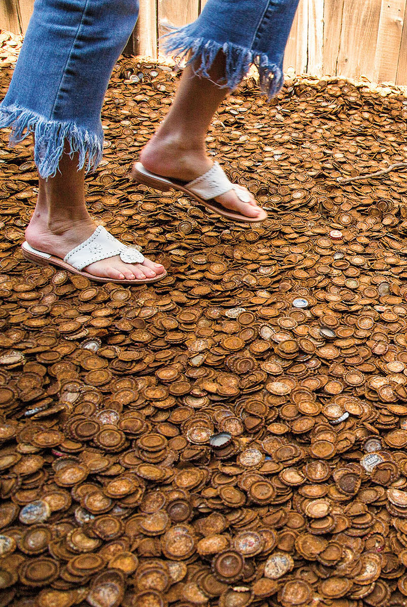 A person walks on a floor covered with brown rusted bottle caps