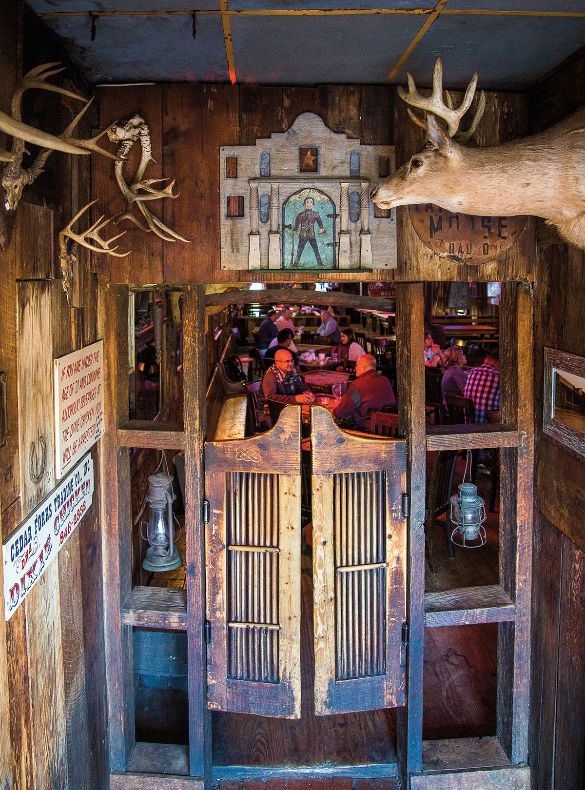 The entryway of an ornately-decorated dive bar with animal heads and wooden saloon doors