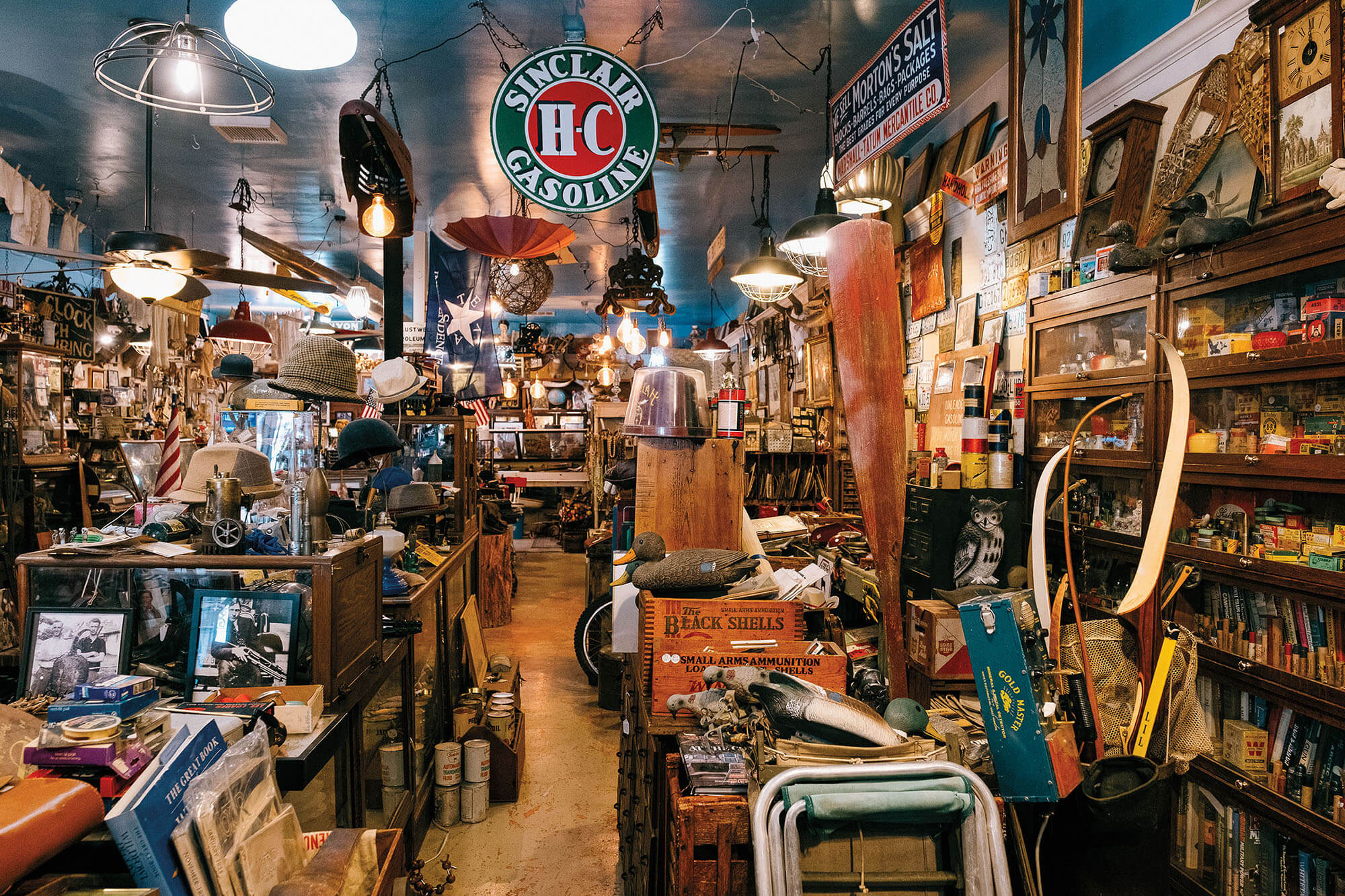 The inside of a cluttered antique store with numerous old signs and products on display