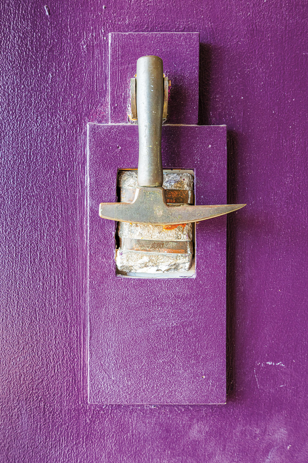A silver tool hanging from a purple door
