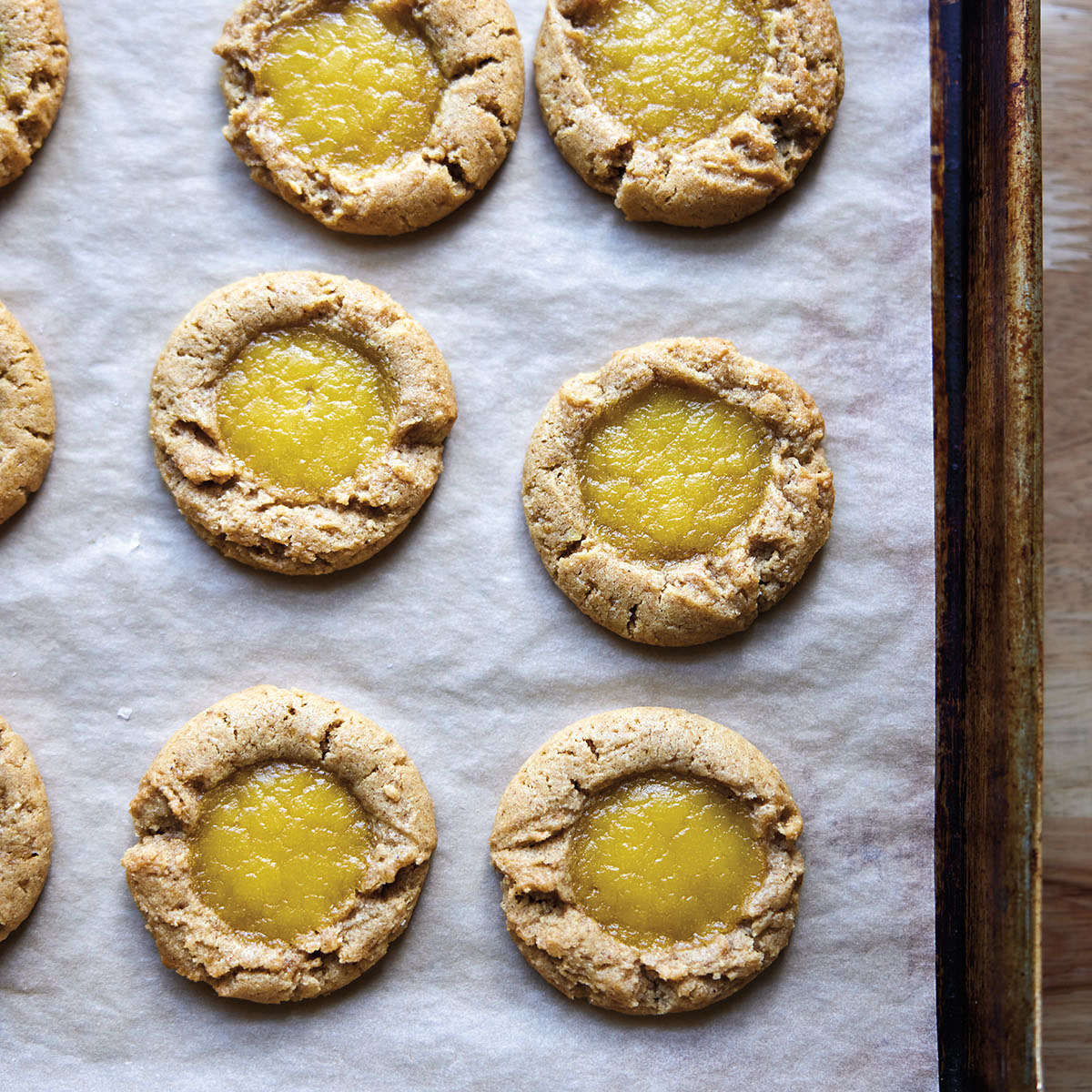 Golden brown cookies on a parchment-lined sheet with a bright yellow center