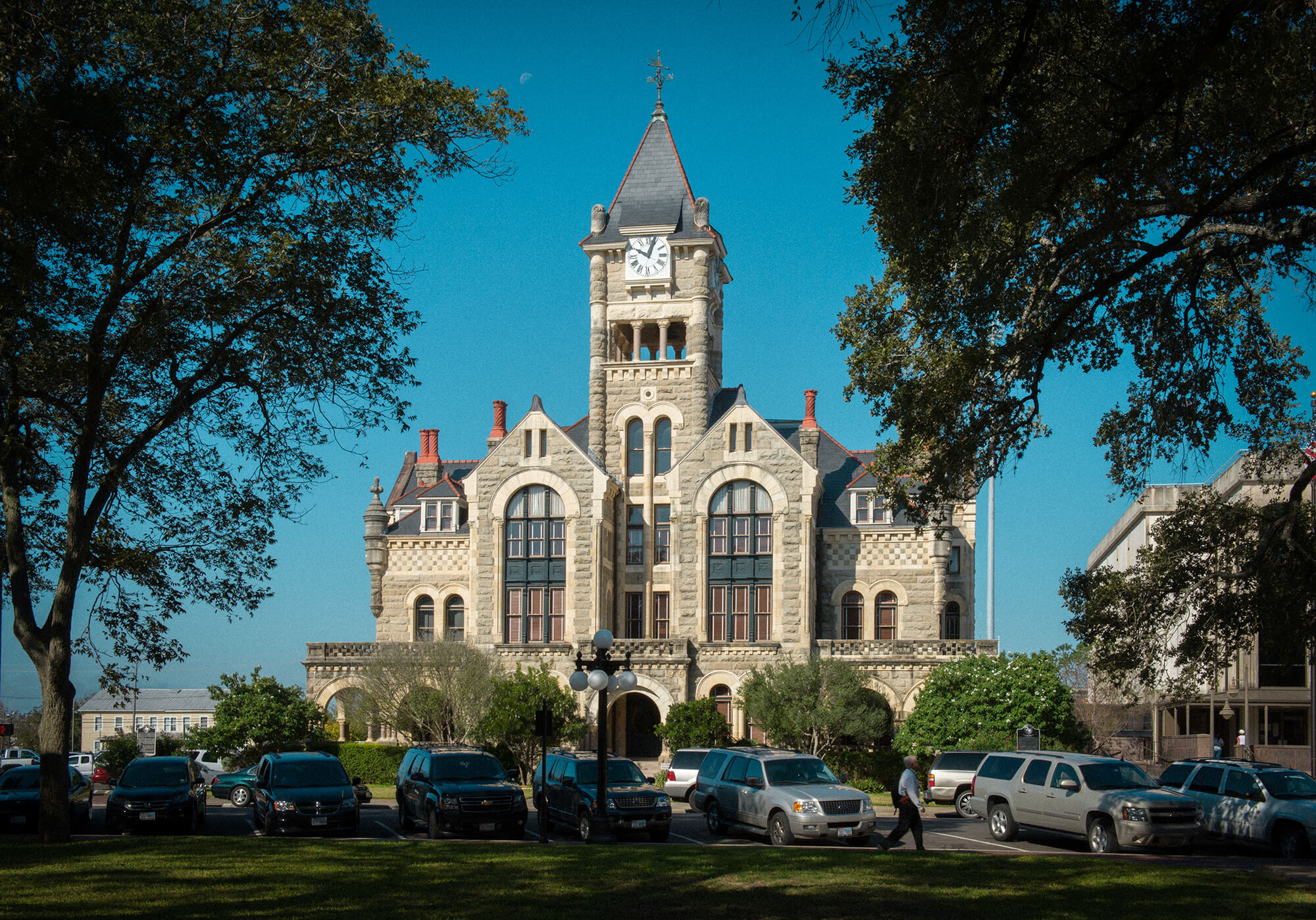 A tall Romanesque courthouse stands center with trees around it