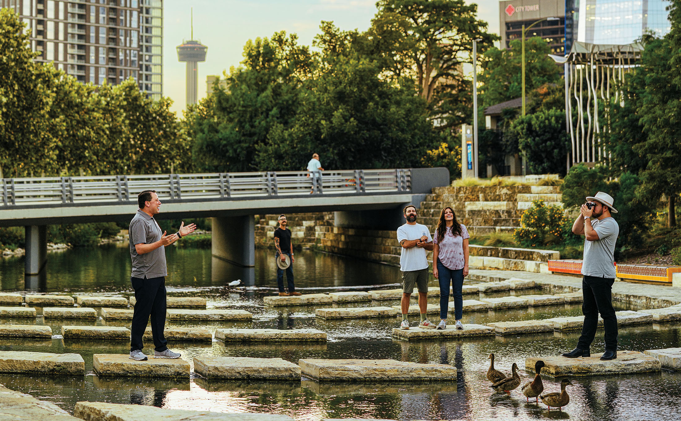 A group of people pose with a tour guide on the water in San Antonio
