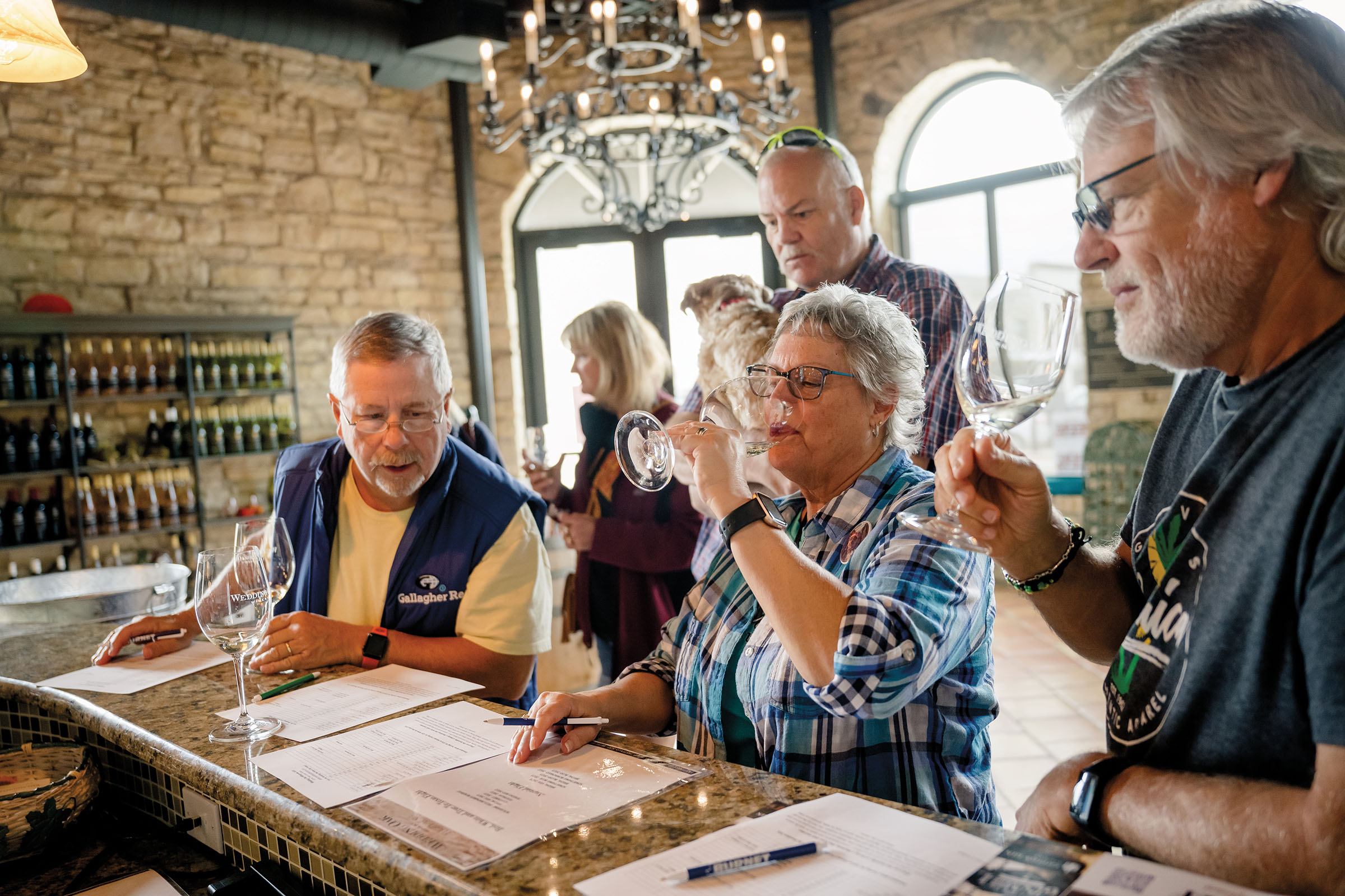 A group of people sit at a bar doing a wine tasting