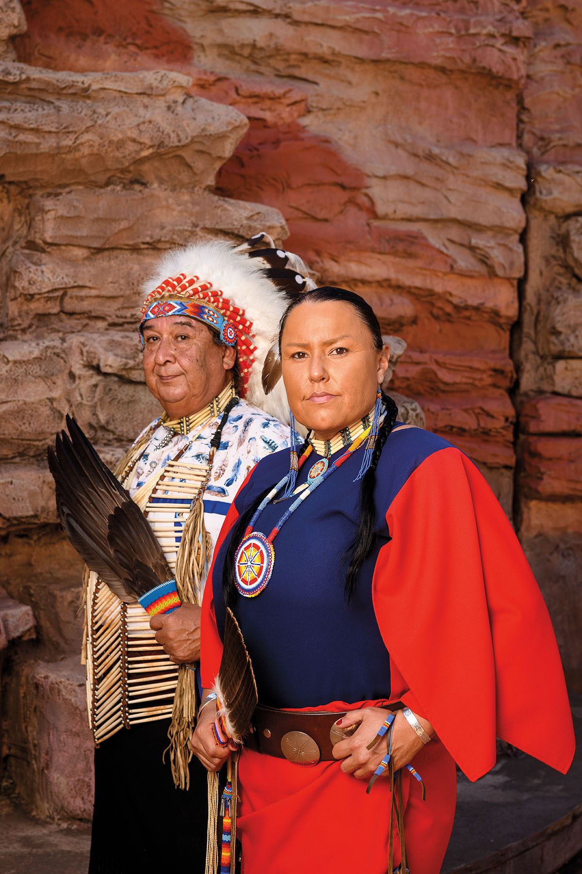 A painting of two Native Americans in front of a stone wall