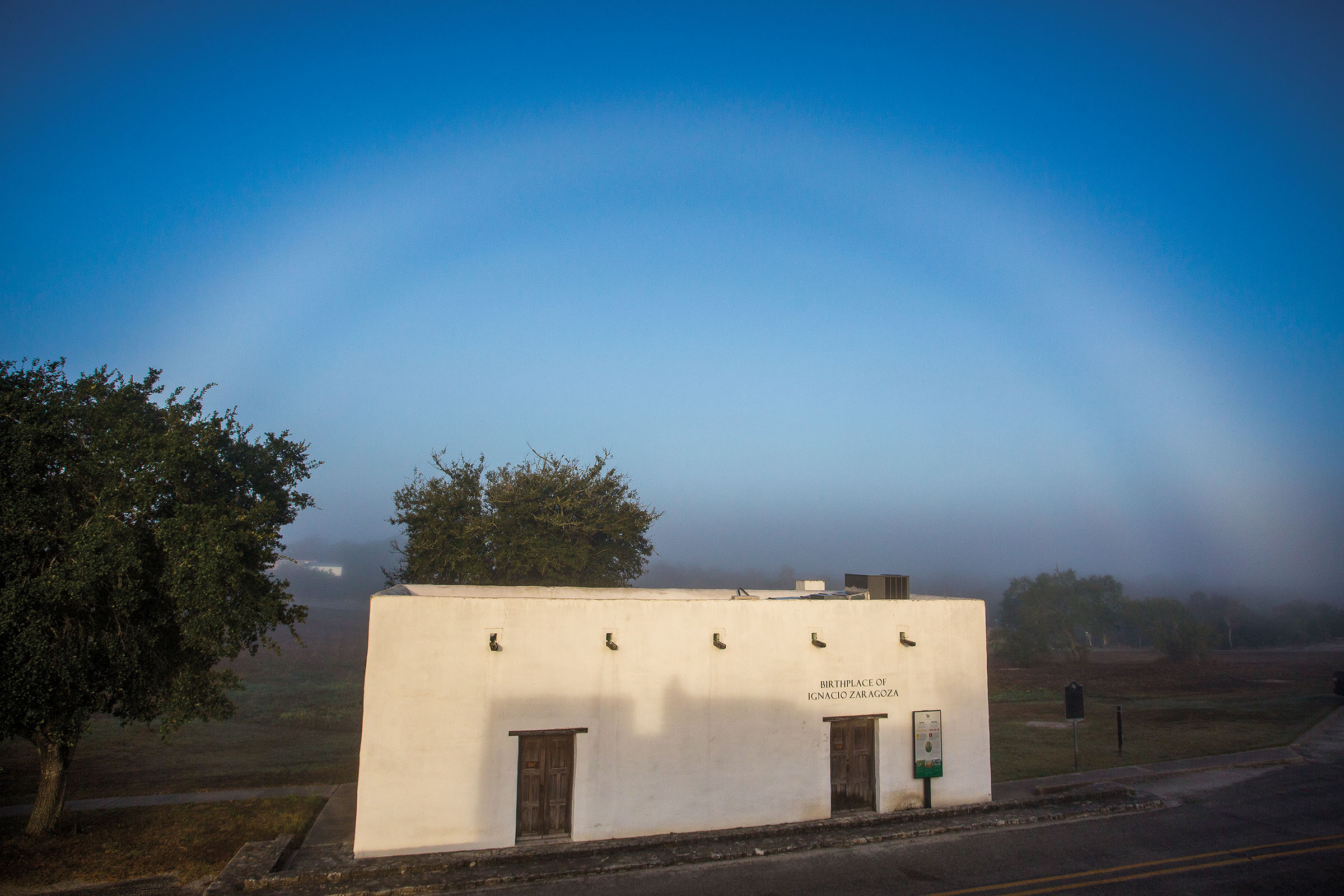 The exterior of a small white adobe building under blue sky