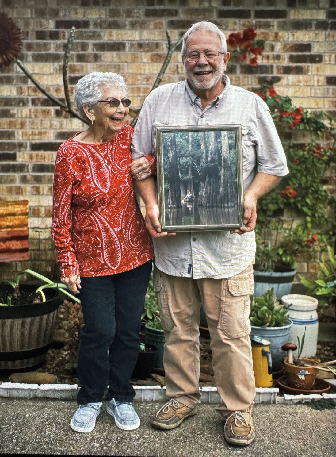 A man stands holding a picture next to an older woman