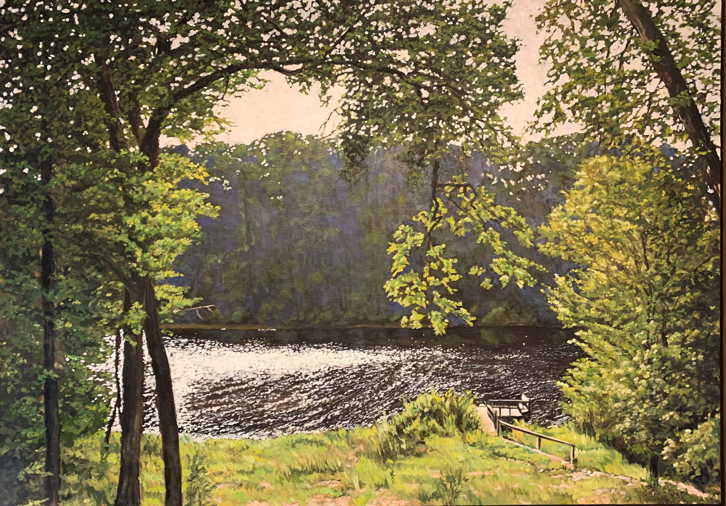 A serene image of green trees and grass and still water