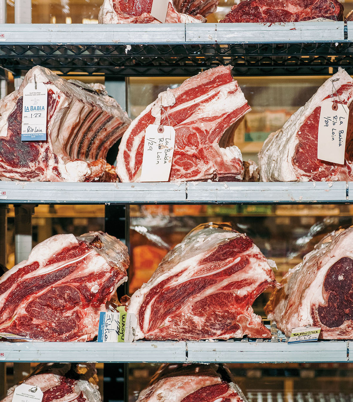 Large red steaks sit in a cooling case