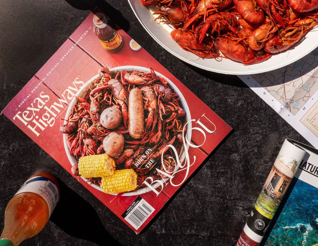 An overhead view of a magazine next to a platter of red crawfish