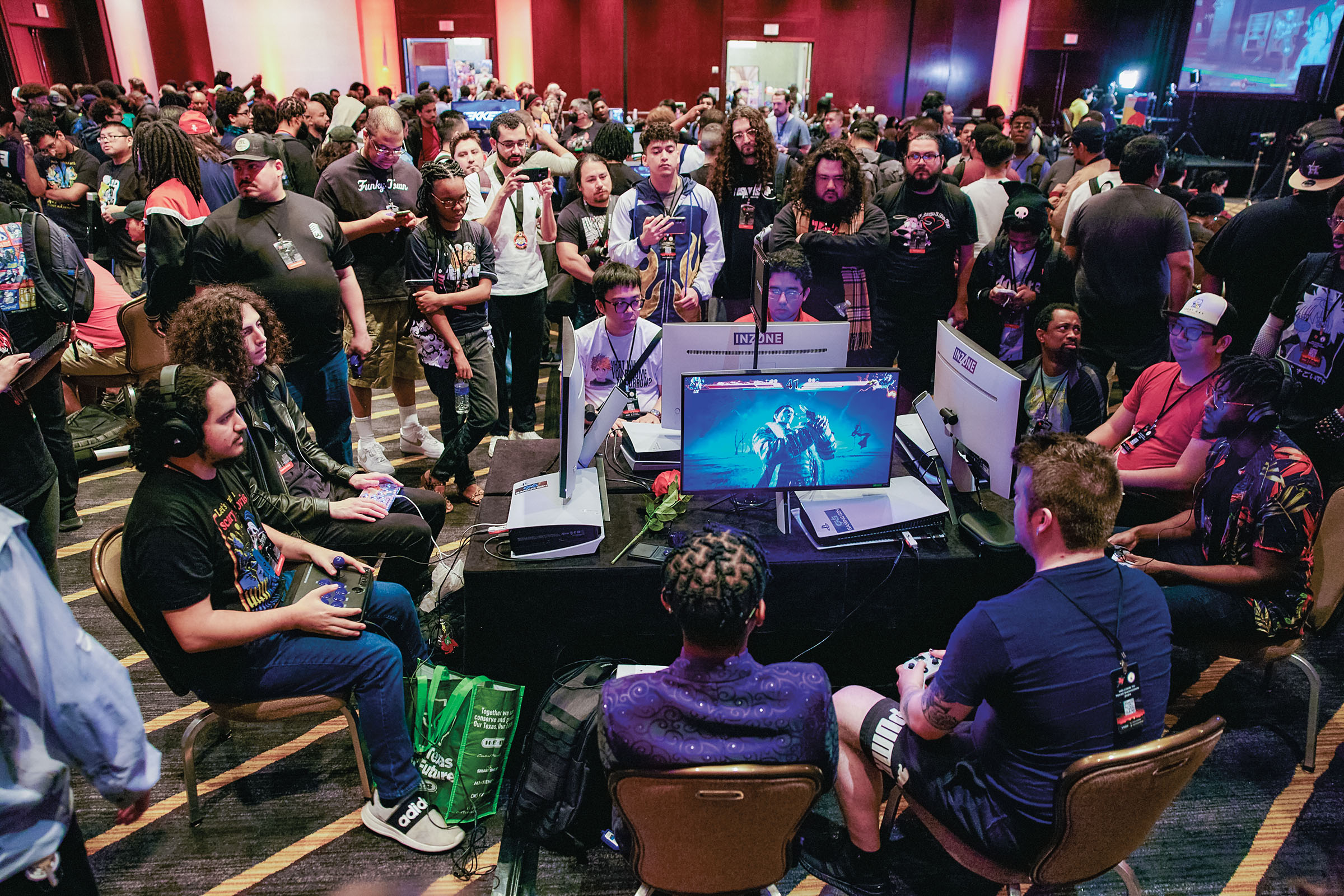 A group of people gather around a smaller group looking at computer screens