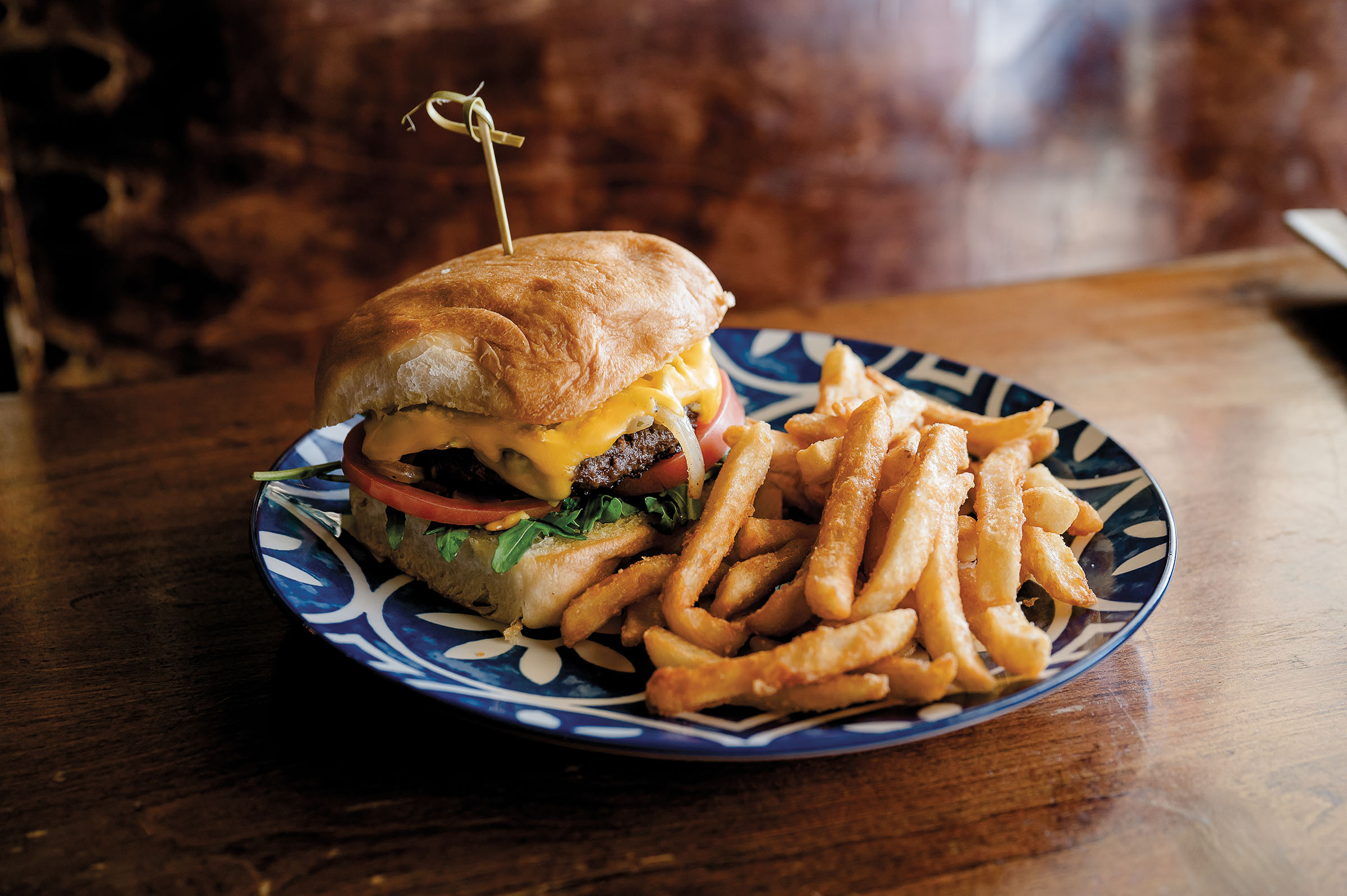 A cheeseburger and fries served on a blue plate on a wooden table