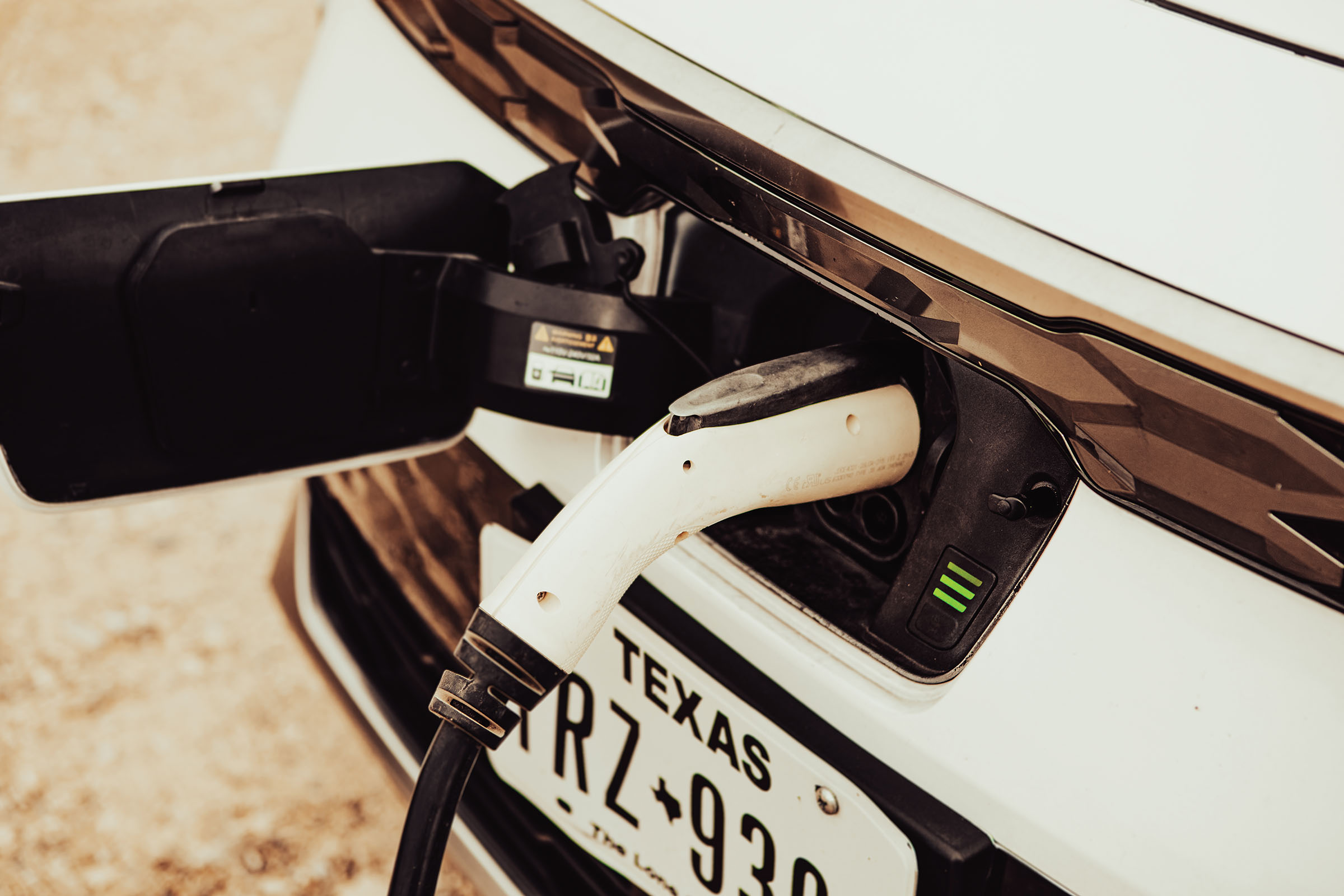 A white charging plug attached to the front connector of the electric vehicle