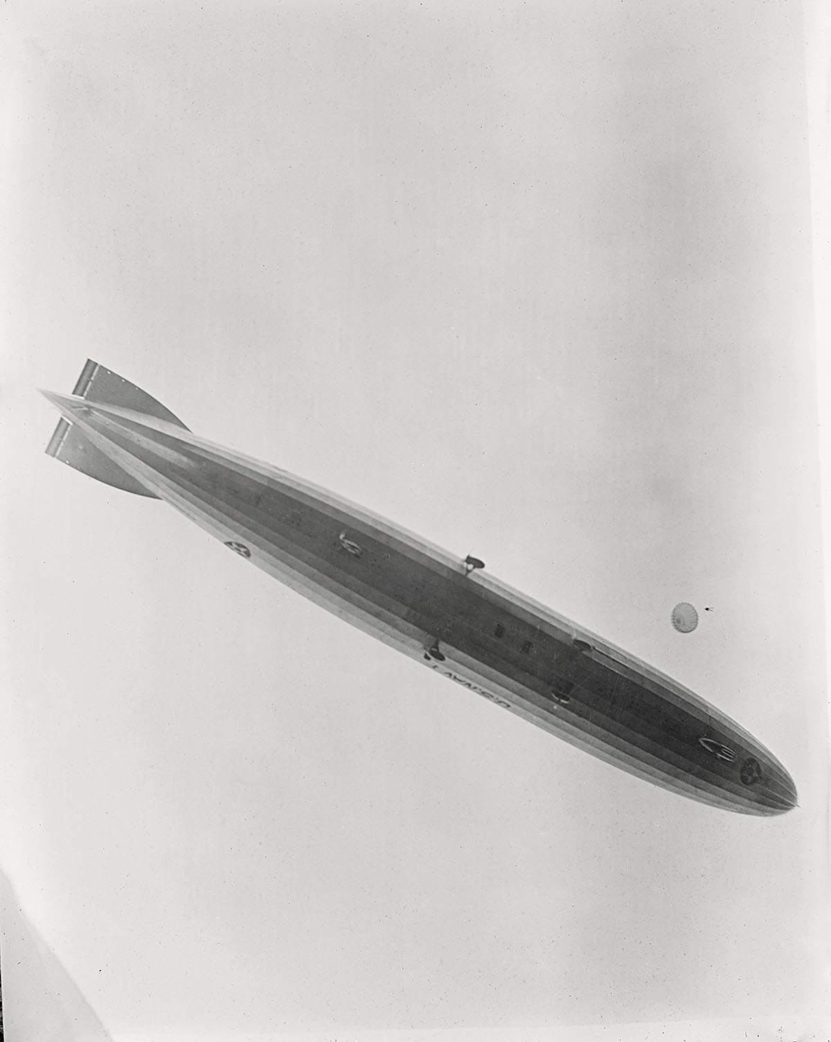 A black and white photograph of a large tube-shaped object flying through the air
