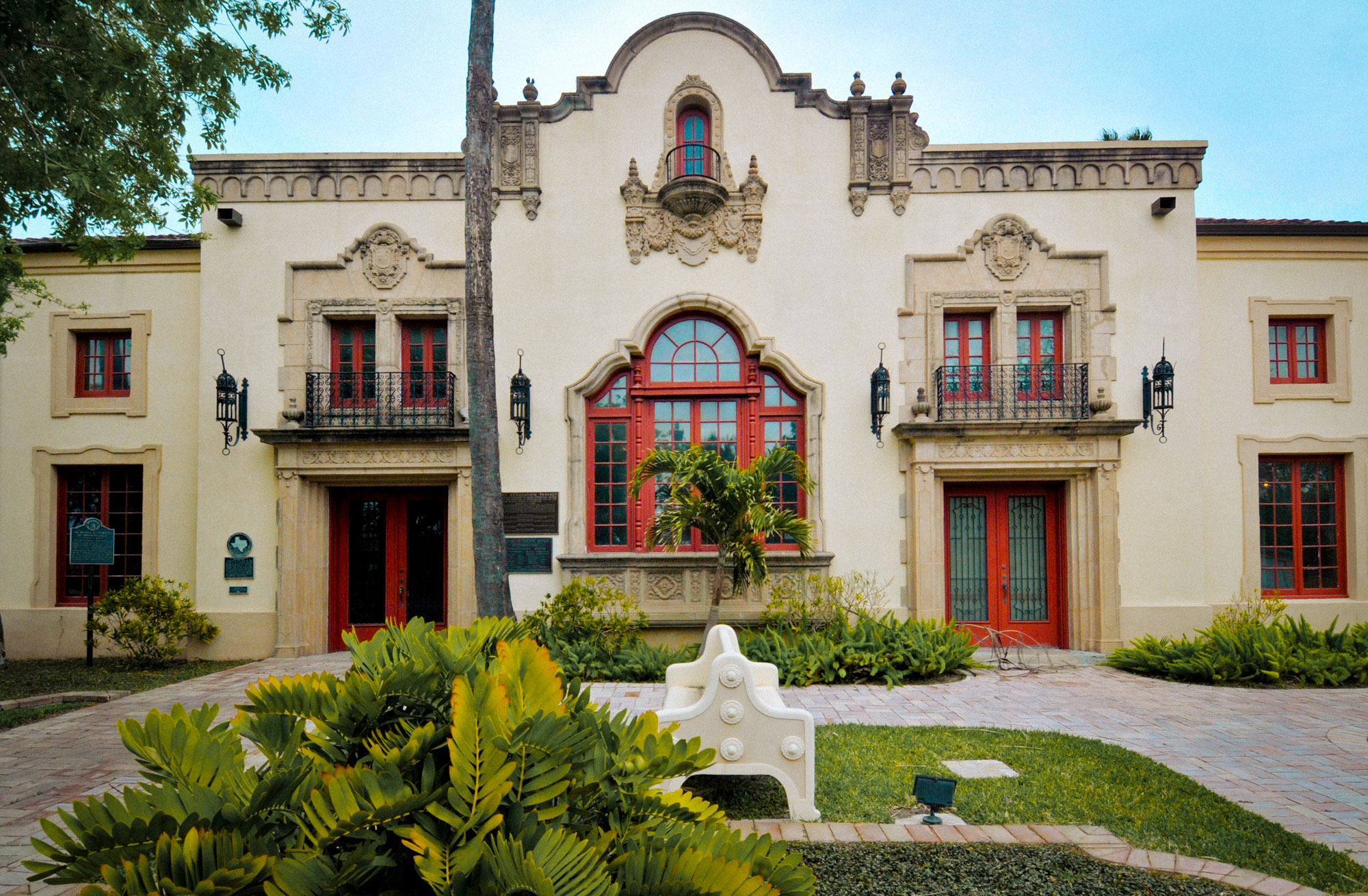 A beige stucco building with red window accents in the Spanish Colonial Revival-style