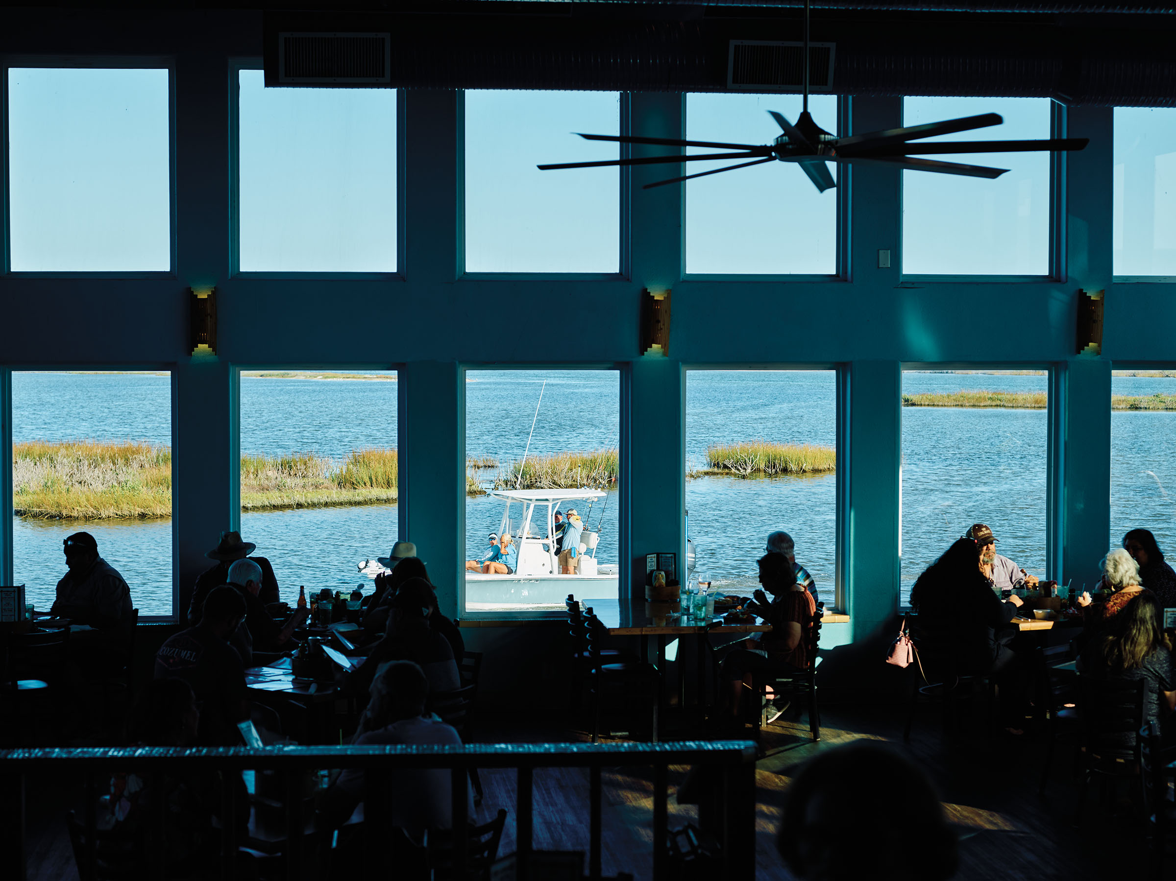 A boat drives by large windows where diners sit
