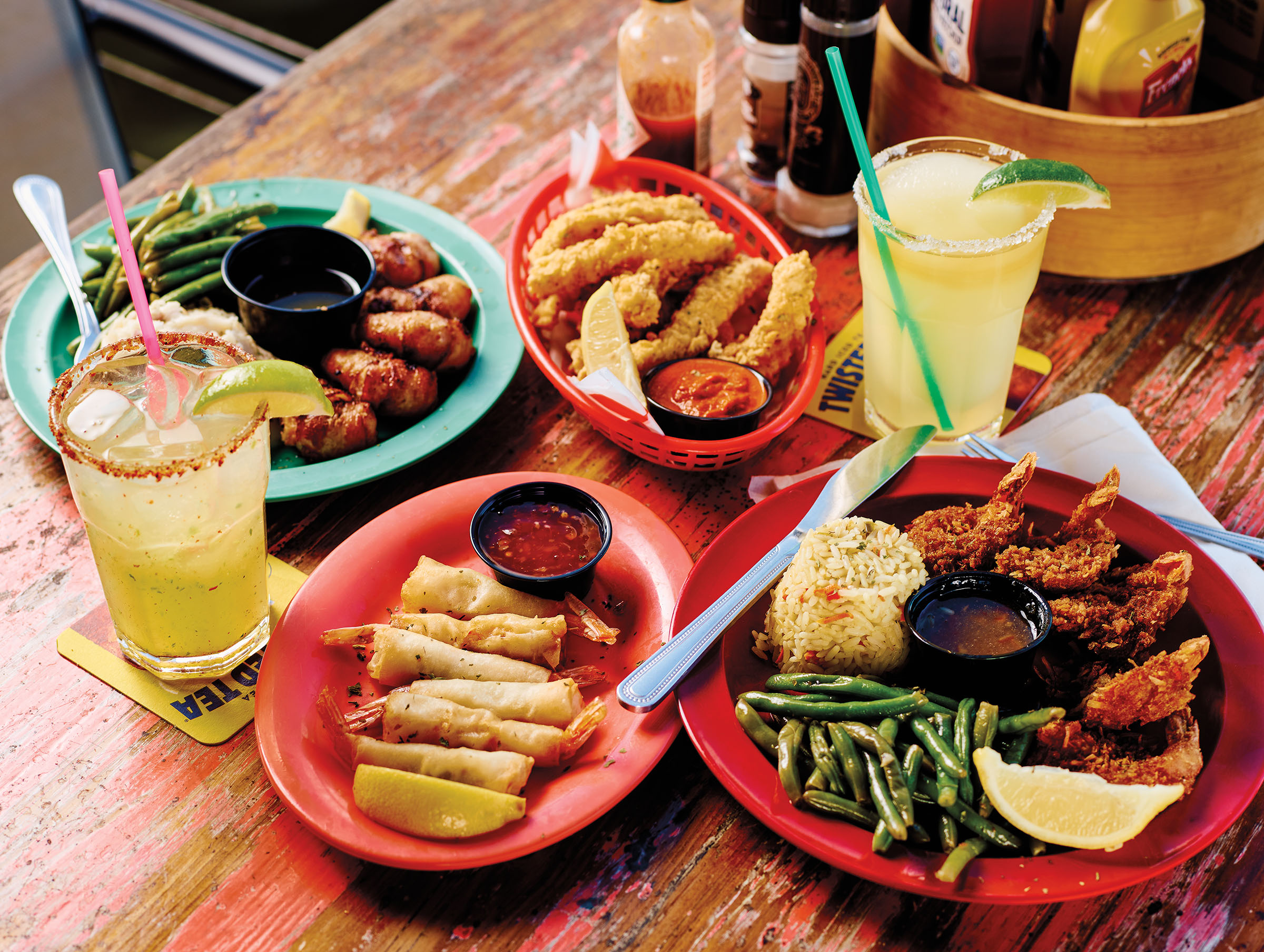 A collection of golden fried seafood on red plates served with a margarita