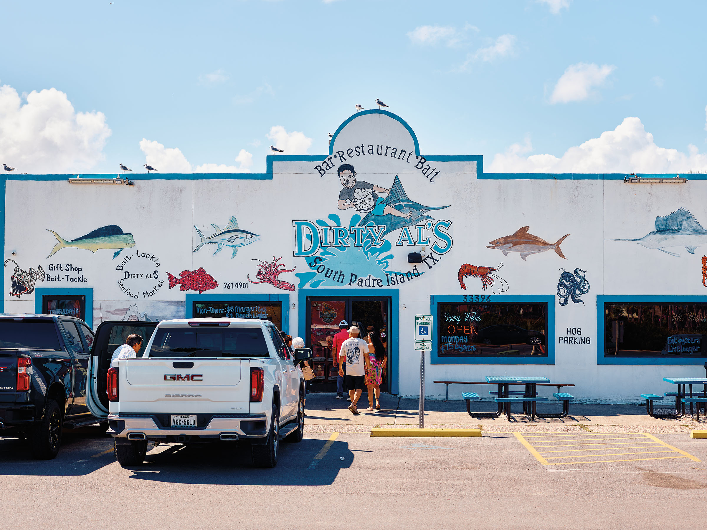 The exterior of a white and blue painted building with a mural reading "Dirty Al's"