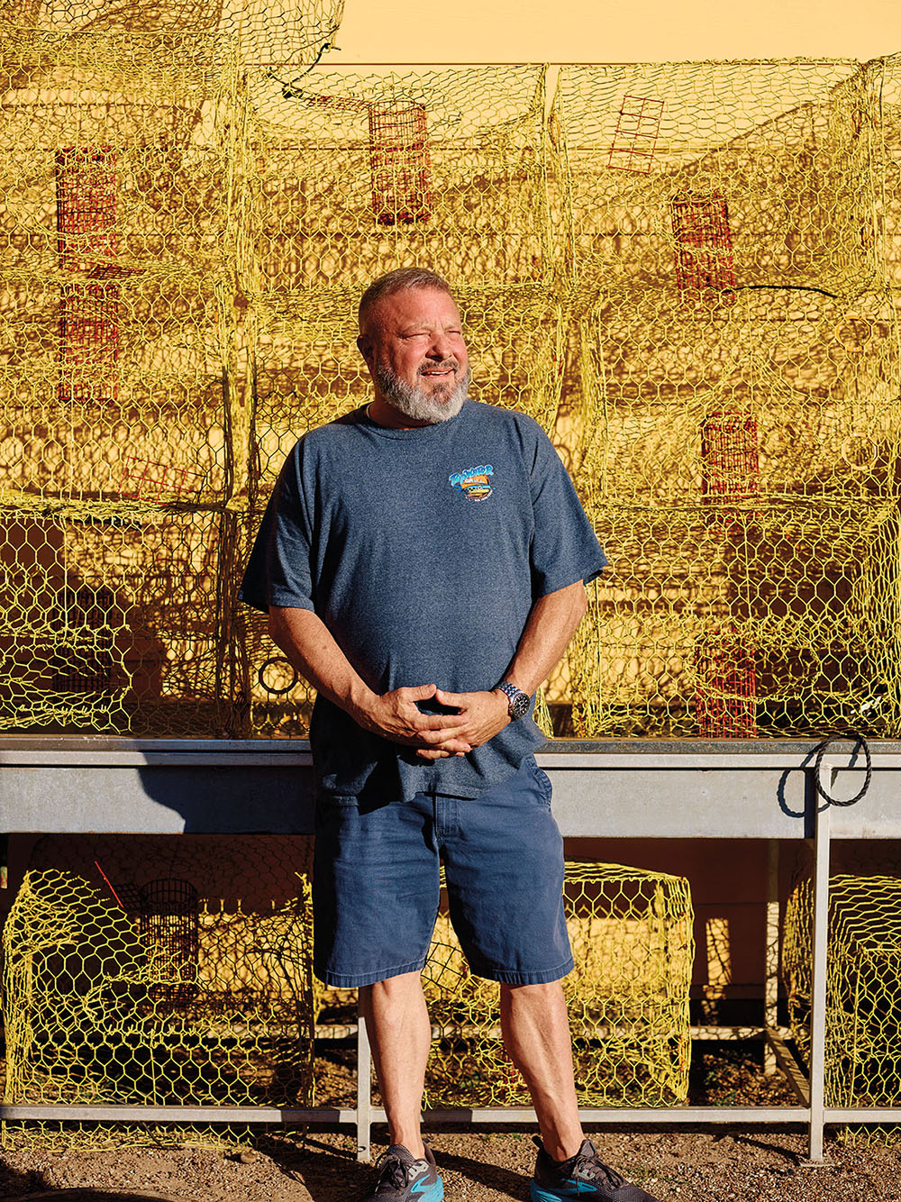 A person in a blue shirt and shorts stands in front of a golden mural
