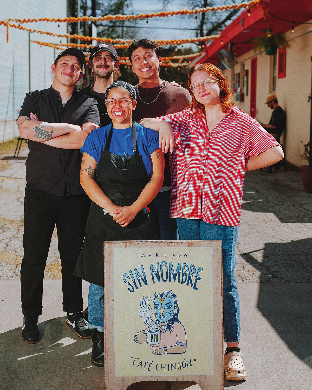 A group of people stand behind a sign on an asphalt parking lot