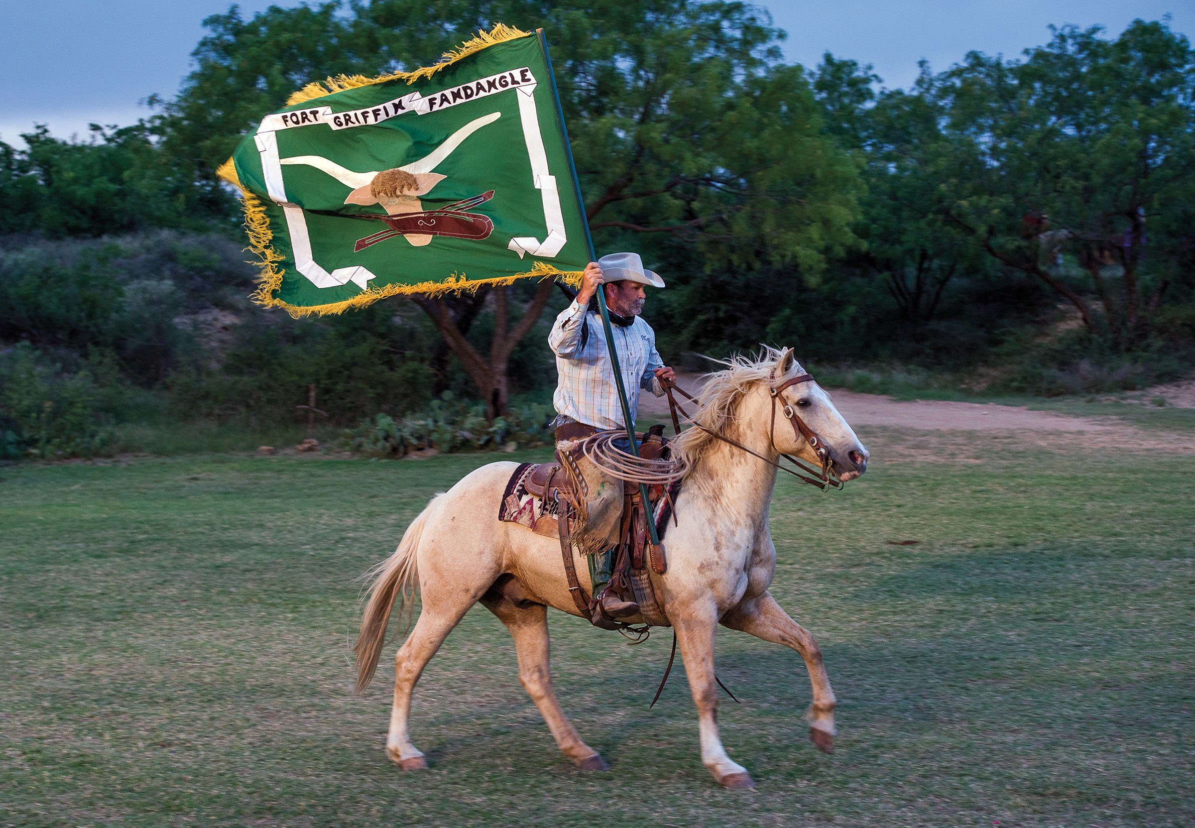 A person riding a horse carring a large green flag